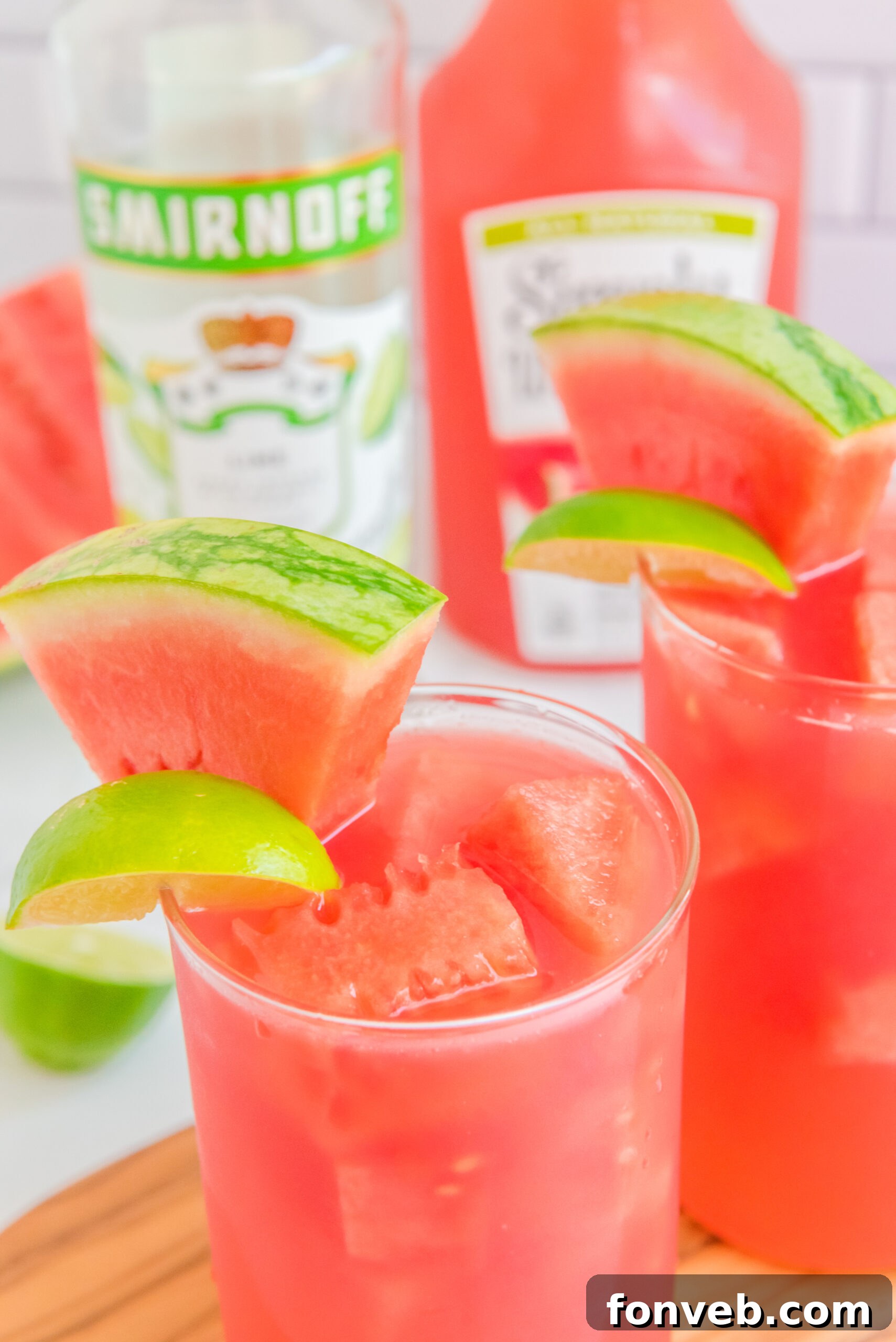 Close up view of Watermelon Cocktail in two clear glasses garnished with lime and watermelon slices.