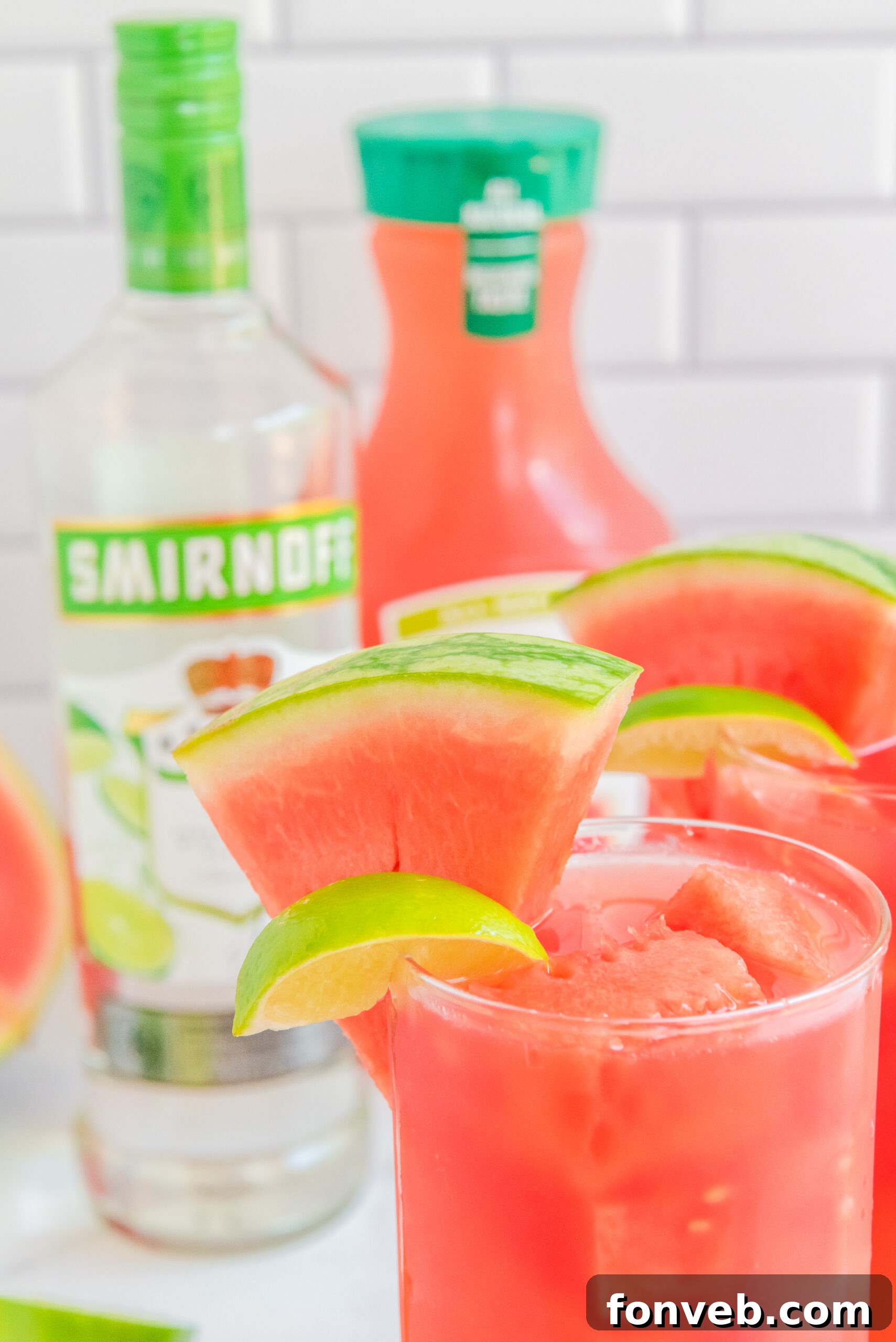 Close up view of Watermelon Cocktail in two clear glasses garnished with lime and watermelon slices.