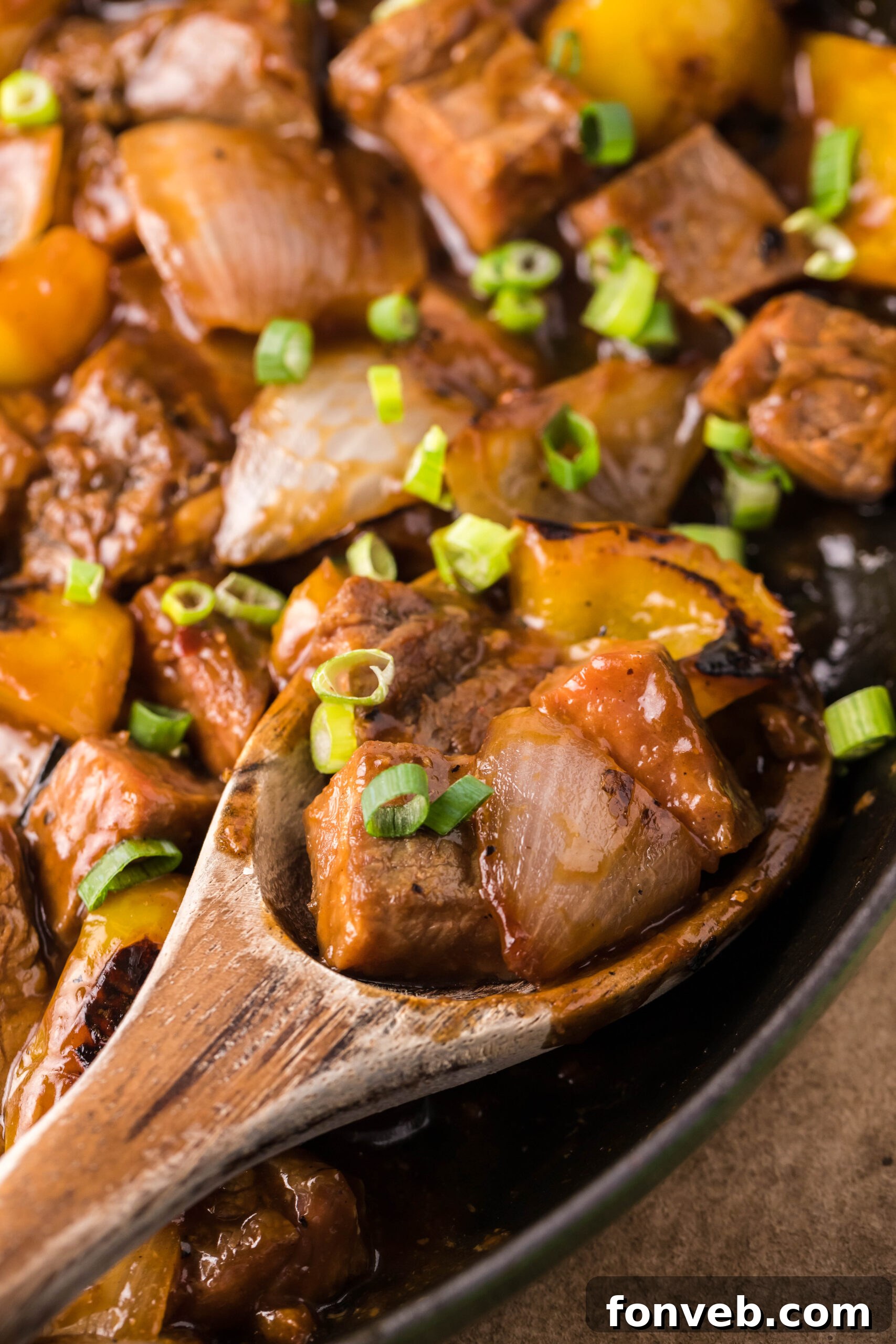 Close up view of a wooden spoon removing a serving of Teriyaki Steak Bites.