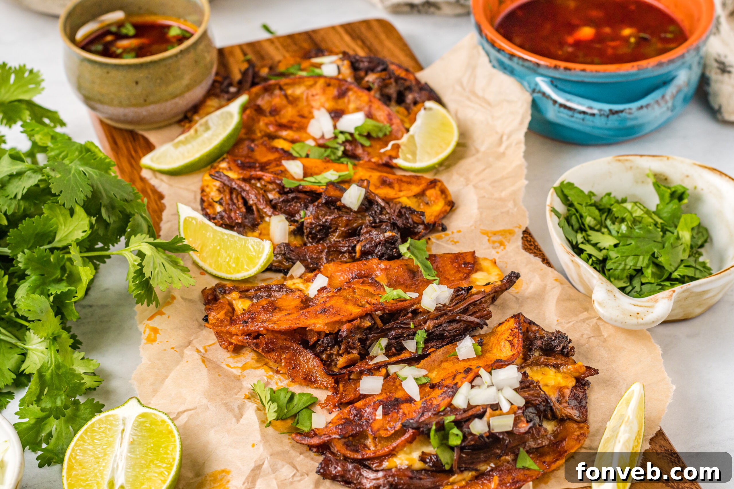Front view of Birria Tacos on a wooden board garnished with onion and cilantro.