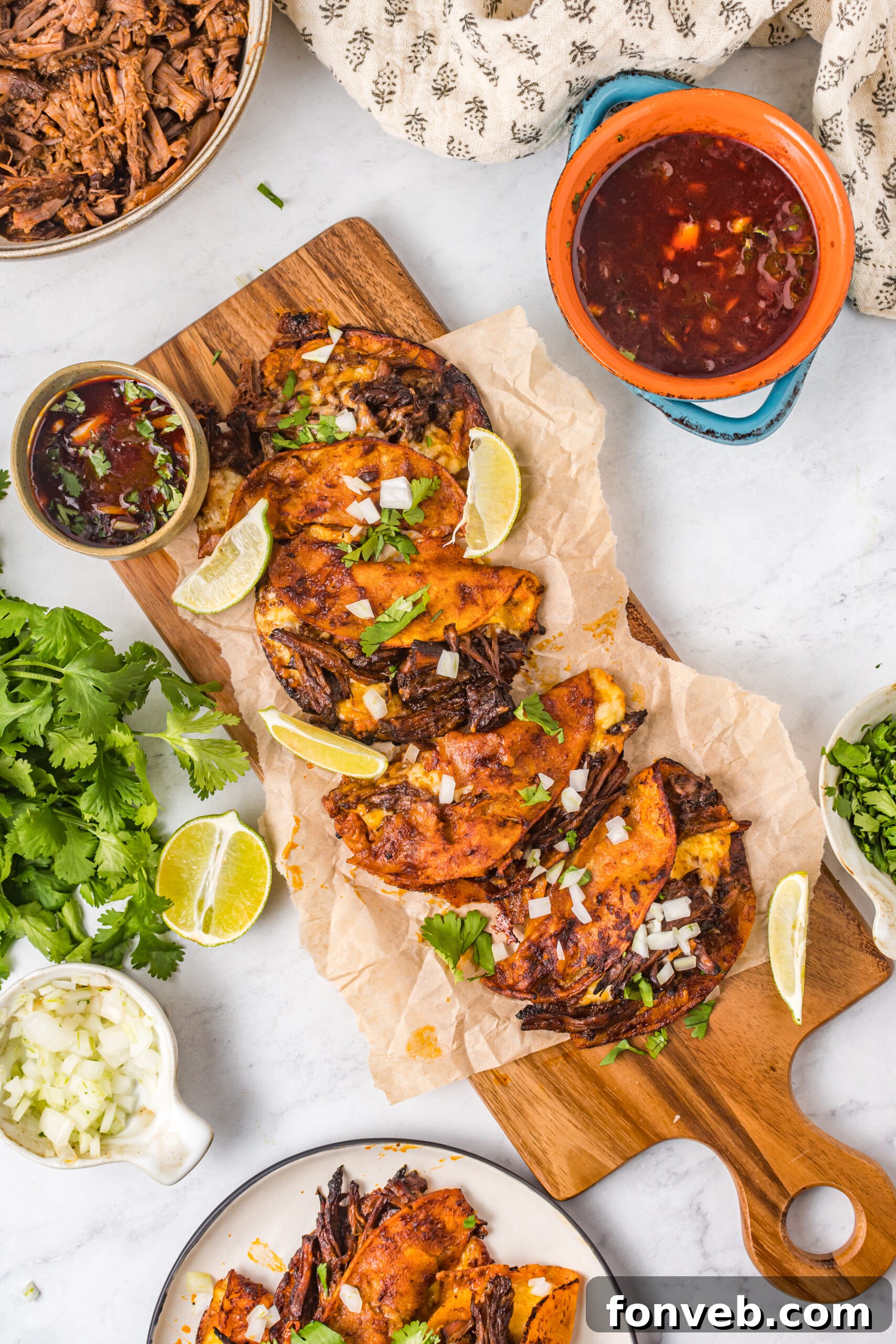 Overhead view of Birria Tacos on a wooden board garnished with onion and cilantro.