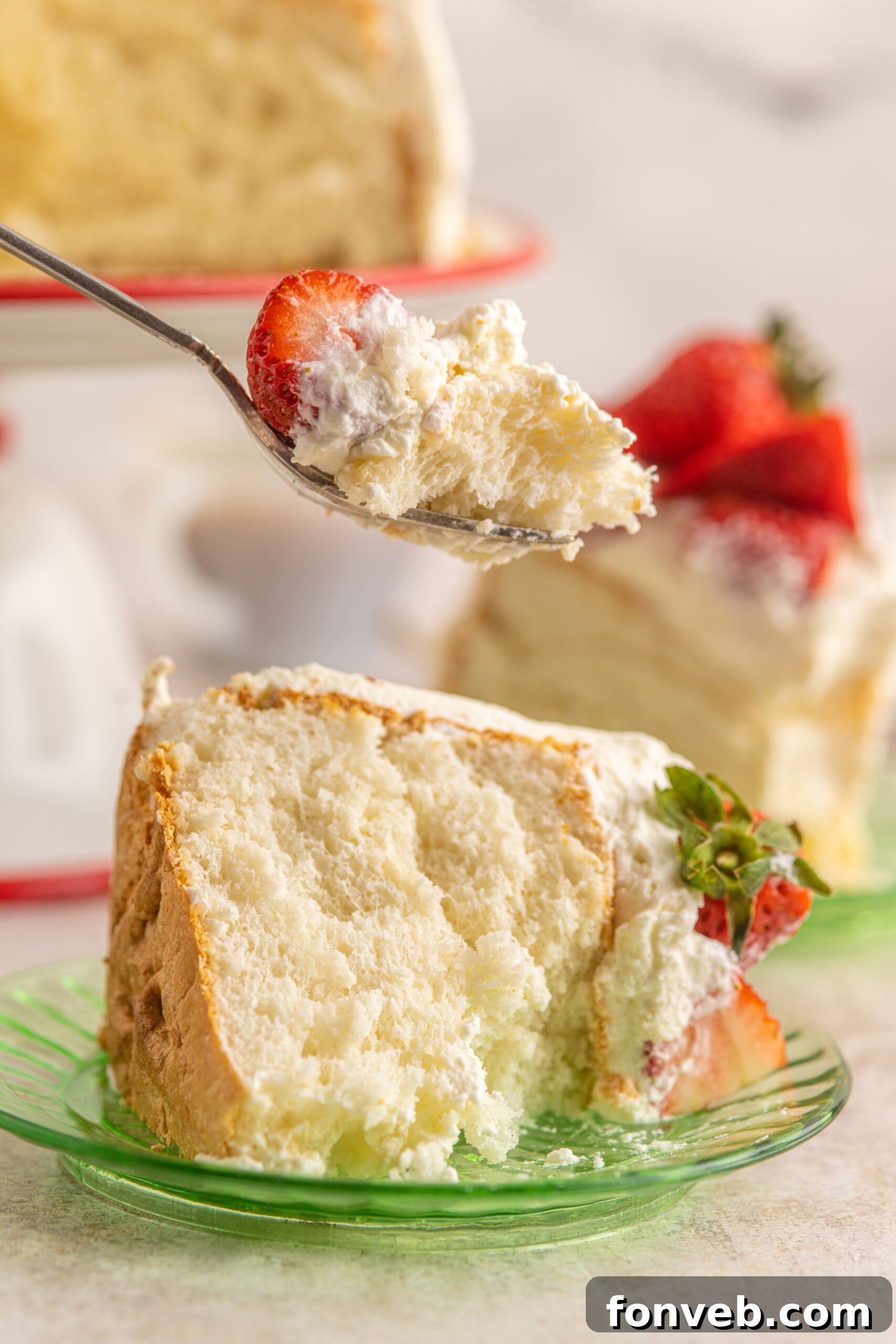 A silver fork removing a bite of Strawberry Angel Food Cake.
