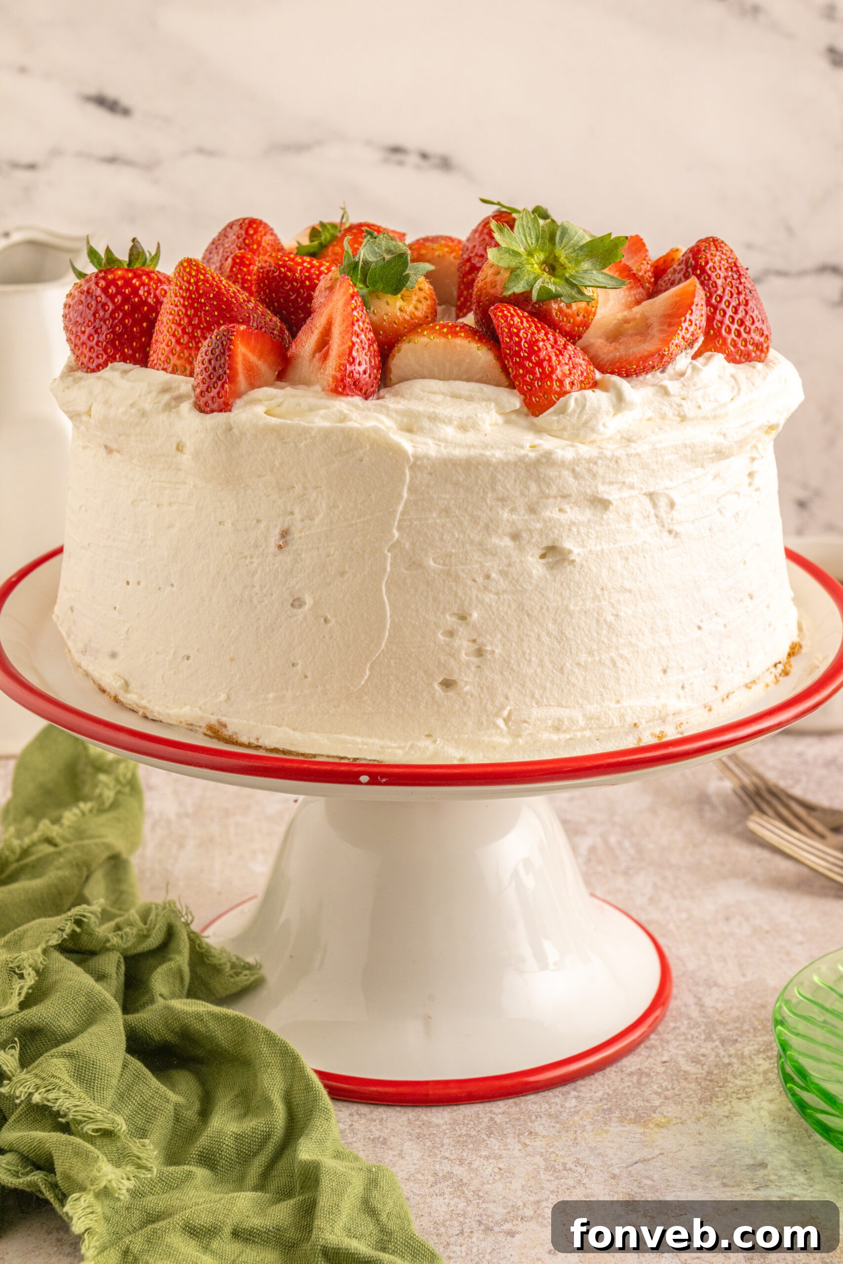 Strawberry Angel Food Cake topped with fresh strawberries and on a cake stand