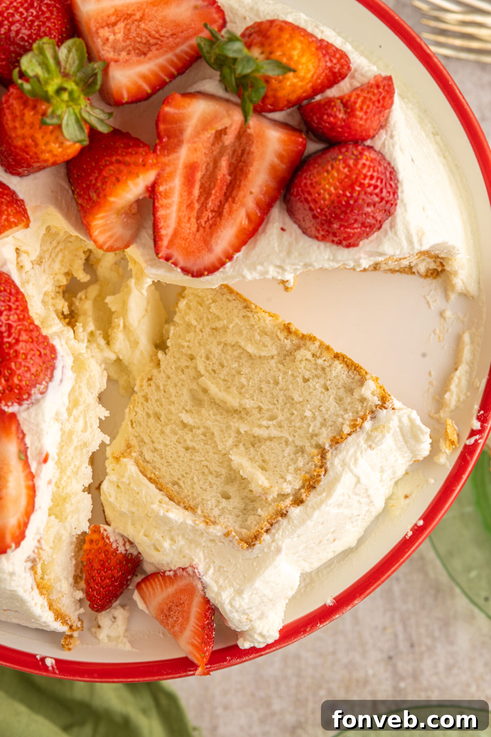 Overhead view of a cut piece of Strawberry Angel Food Cake on a white and red cake stand. 