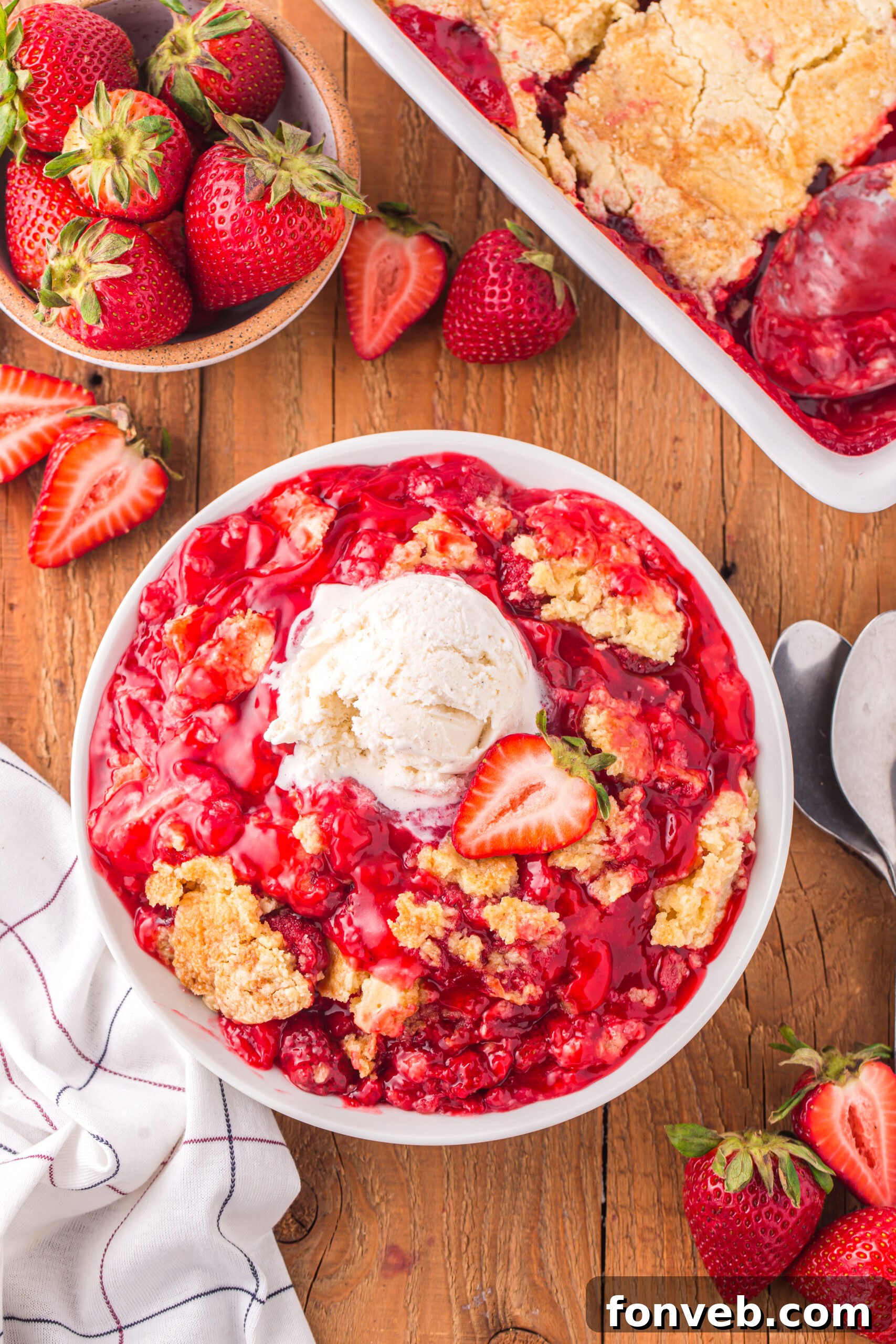 far away overhead view of a serving of Strawberry Dump Cake in a white bowl topped with a scoop of ice cream.