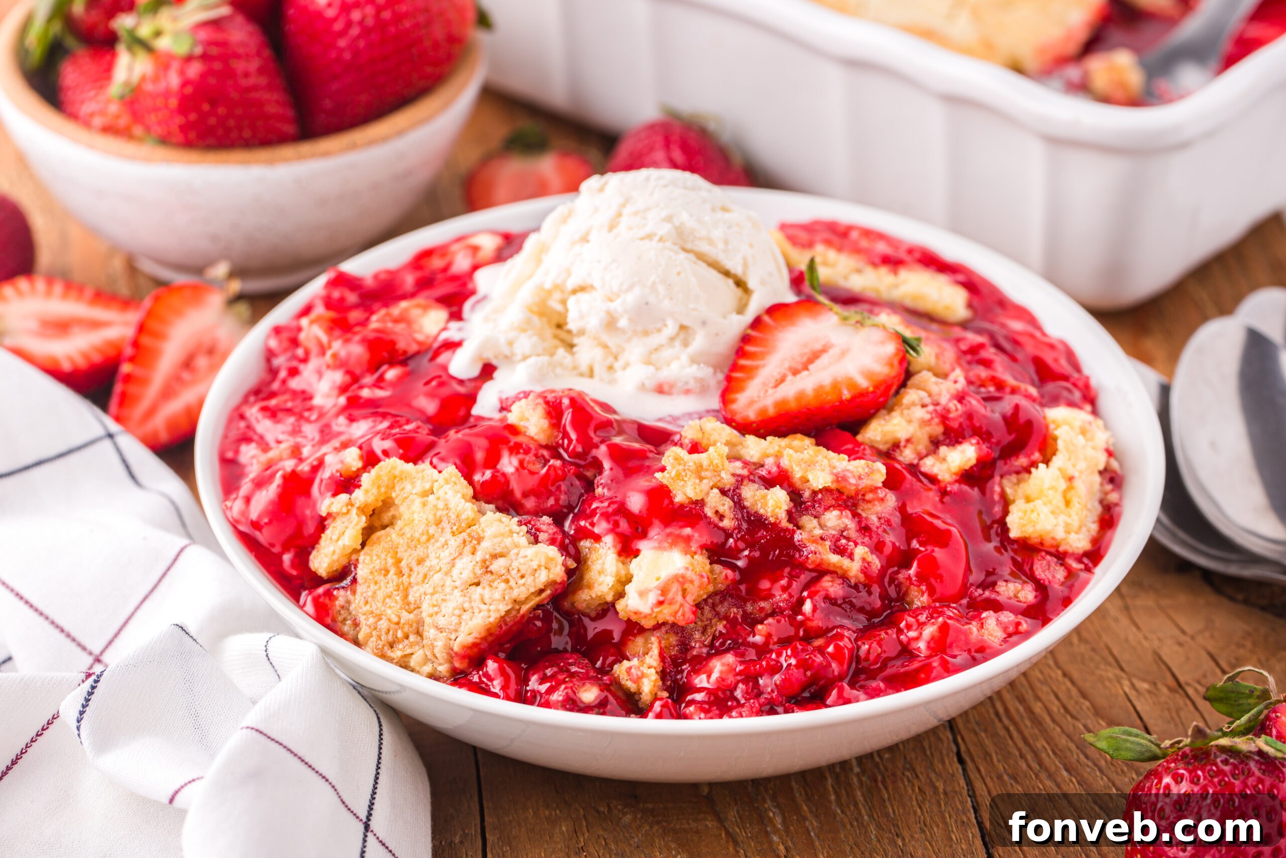 Front view of a serving of Strawberry Dump Cake in a white bowl topped with a scoop of ice cream.