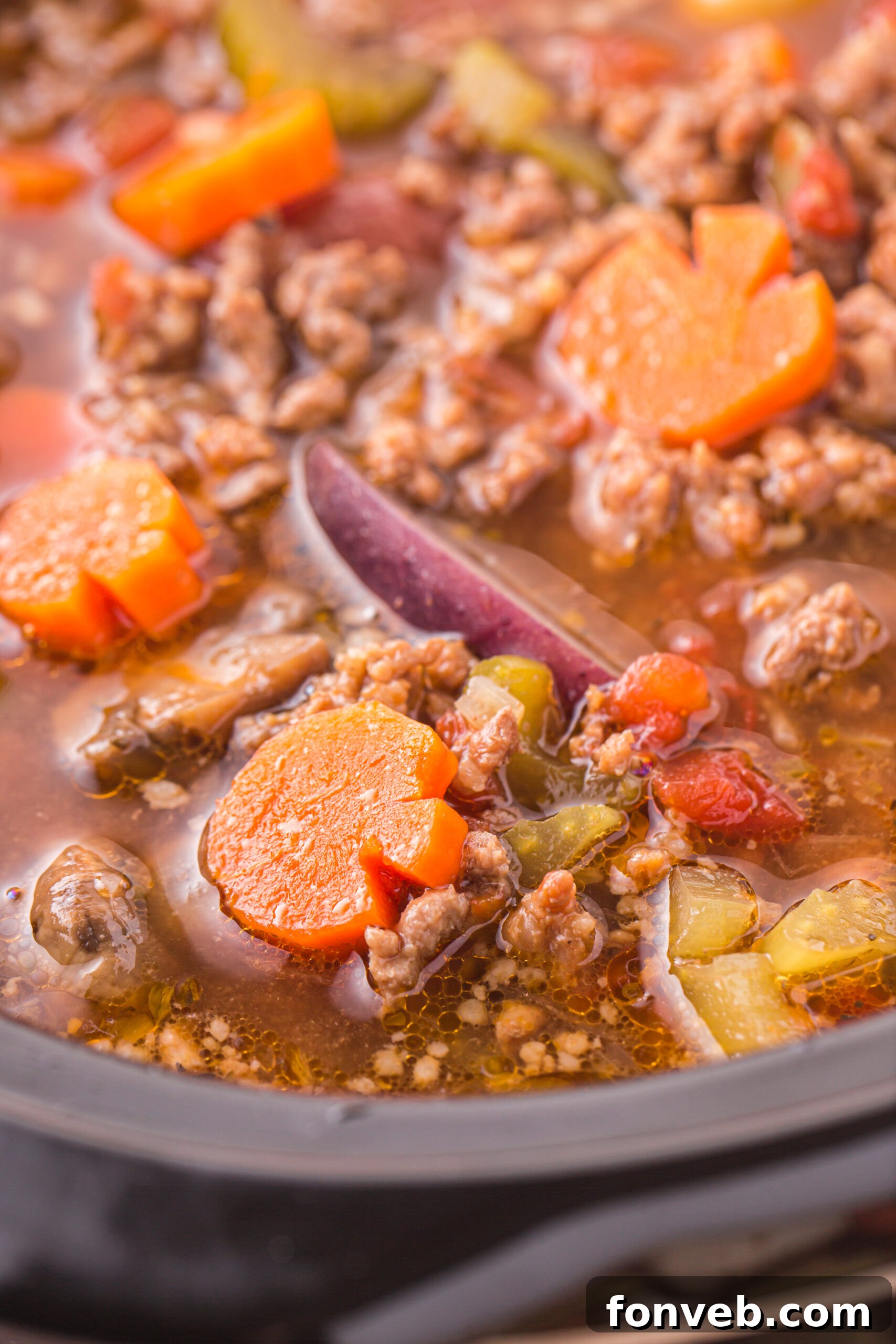 Close up view of the bubbling Witches Brew Stew in a slow cooker, showing meat and vegetables.