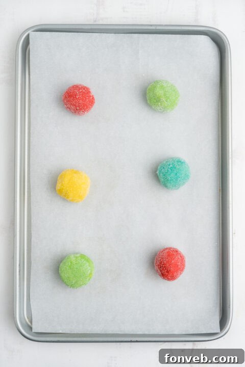 Vibrant Jello Bites 11 Step-by-step image of rolling Jello cookie dough balls in granulated sugar before baking.