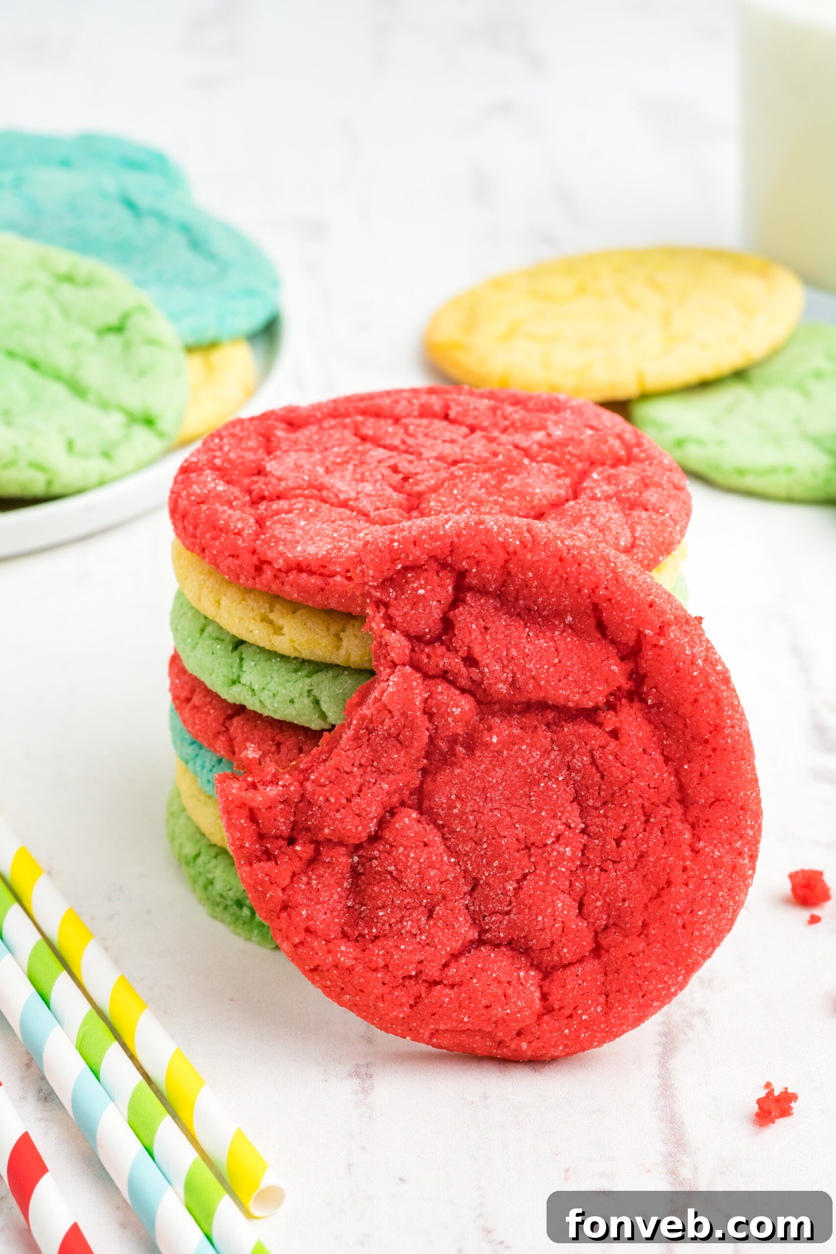 Vibrant Jello Bites 16 Front view of a Jello Cookie with a bite removed, propped on a stack of other colorful cookies, highlighting its soft interior.
