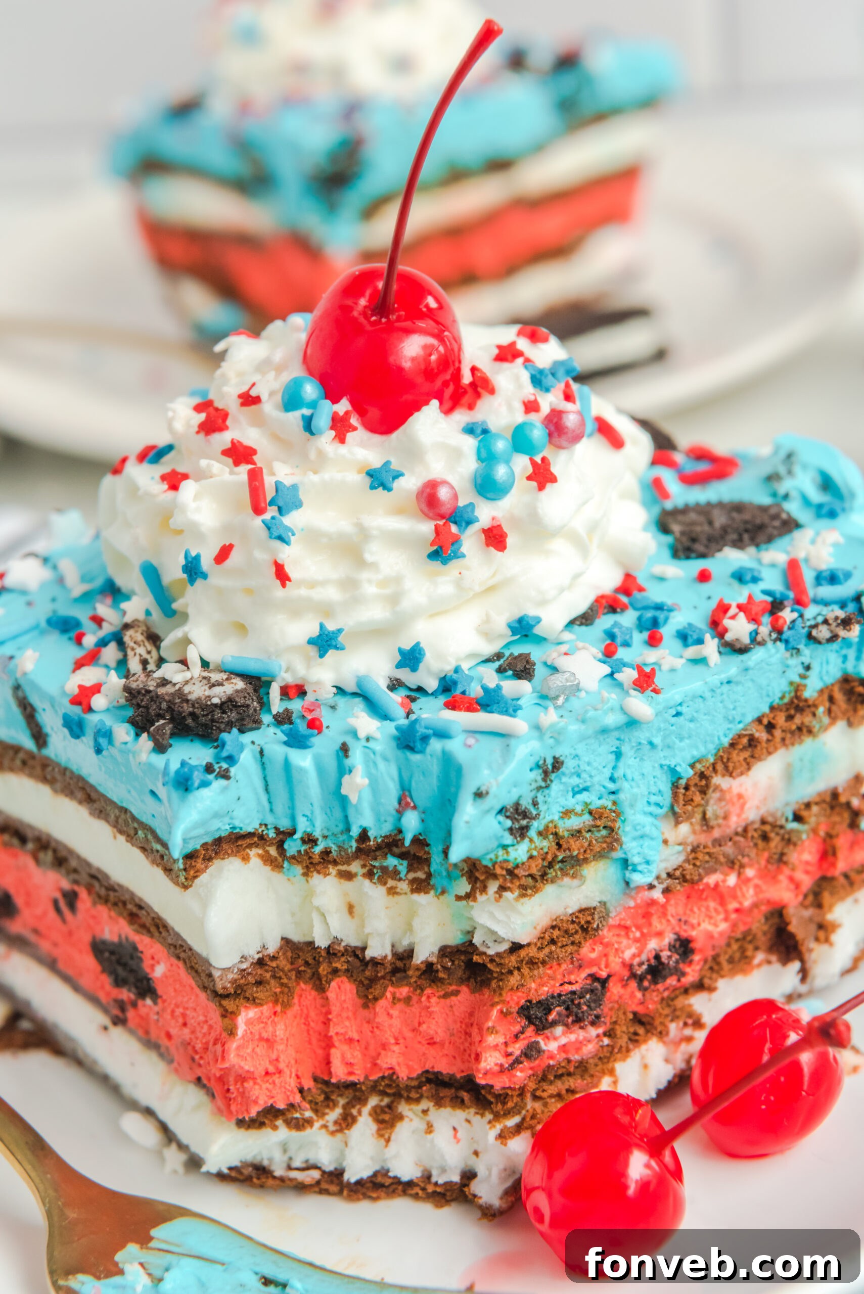 Overhead view of a slice of Patriotic Ice Cream Sandwich Cake topped with whipped cream and cherry.