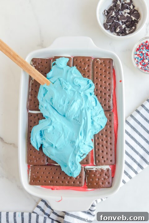 Spreading the red layer of the cake filling over the ice cream sandwiches.
