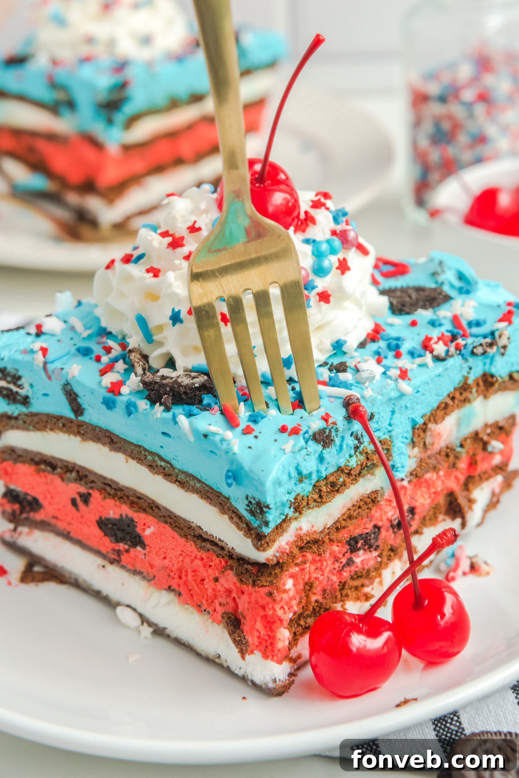 Front view of a slice of Patriotic Ice Cream Sandwich Cake with a silver fork removing a bite.
