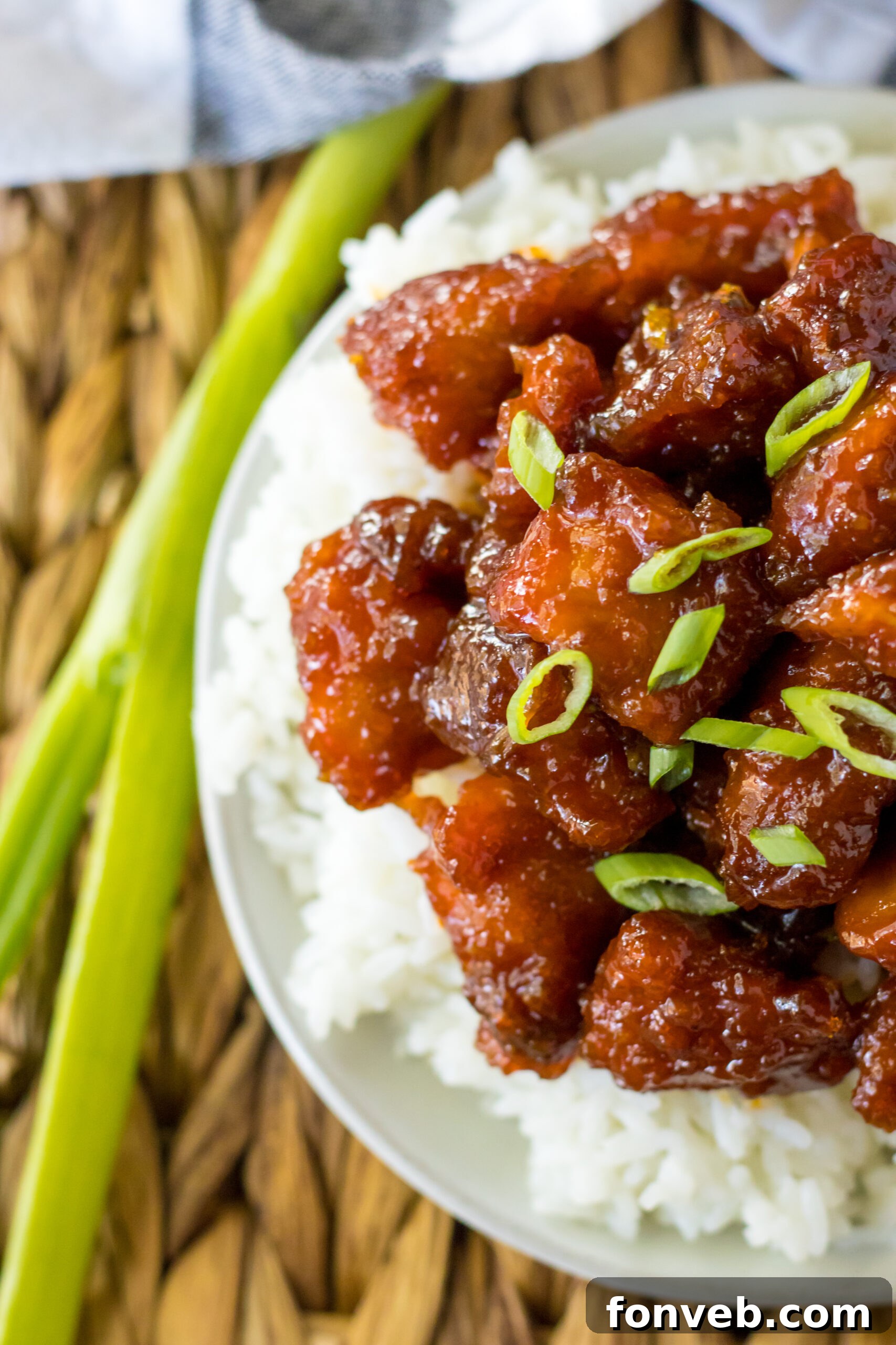 Close up view of Slow Cooker Firecracker Chicken over white rice in a white bowl, showing tender chicken pieces.