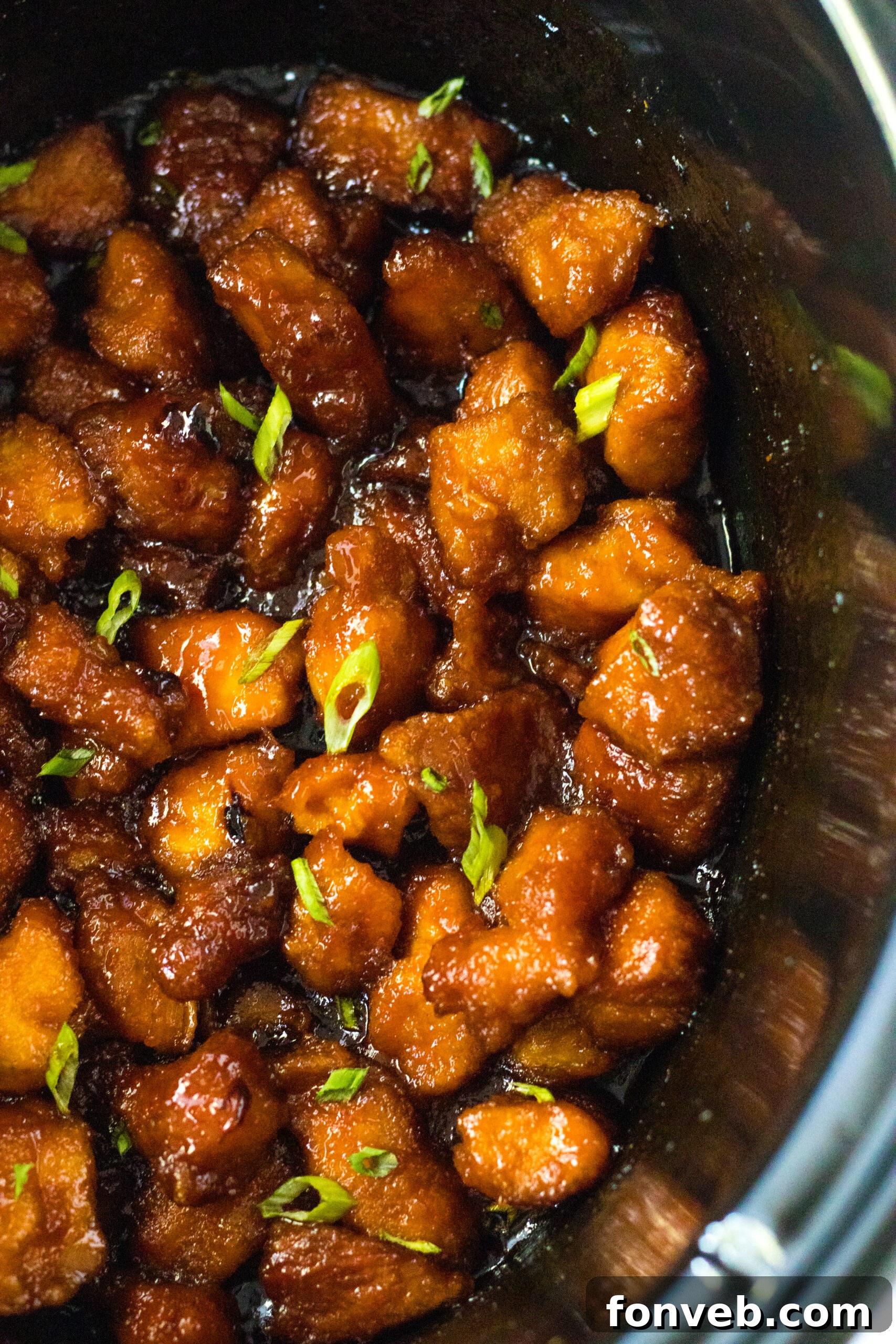 Overhead view of Slow Cooker Firecracker Chicken simmering in a crock pot, rich sauce visible.