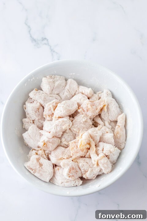 Chicken browning in a skillet on the stovetop.