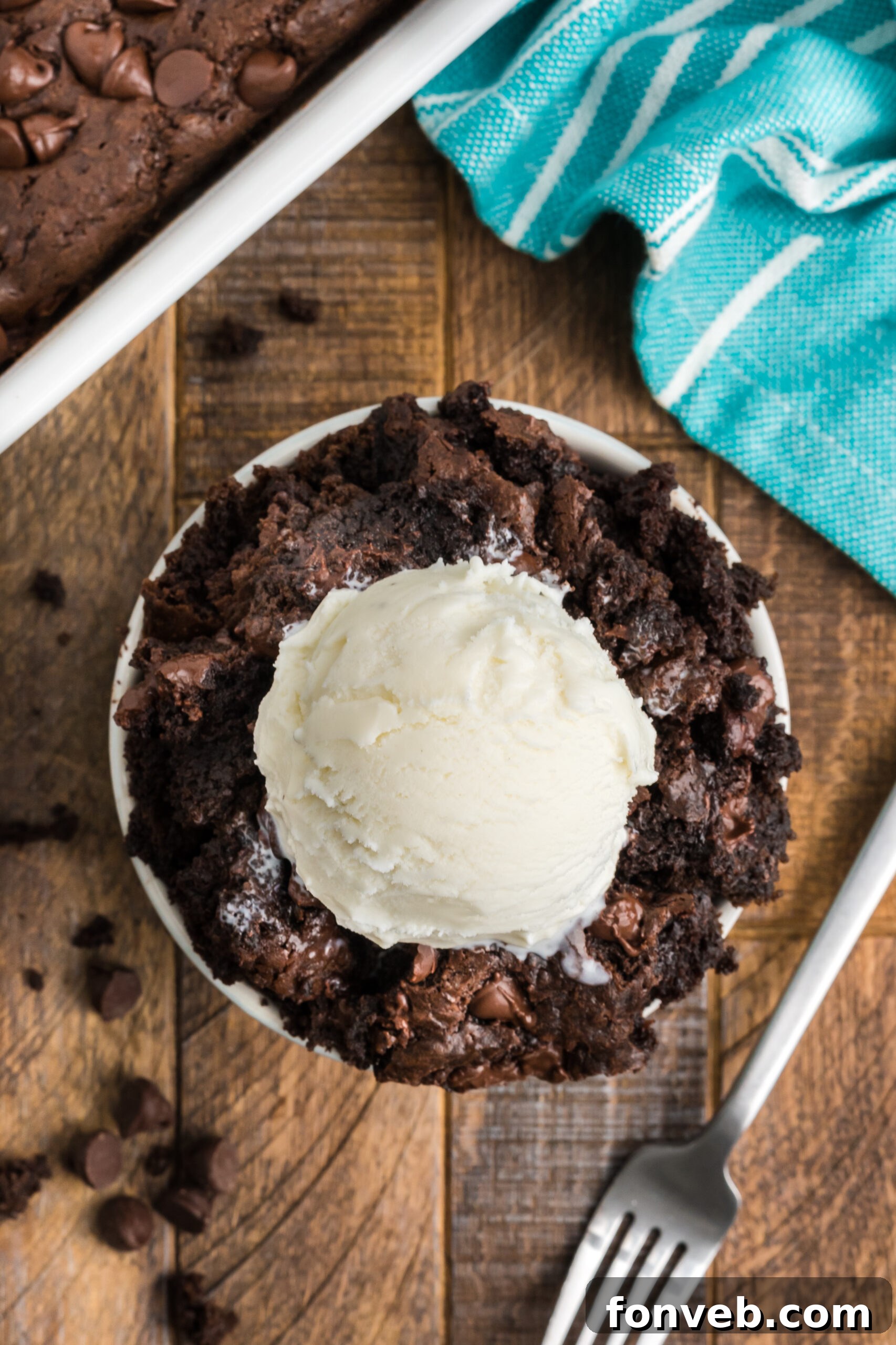 An overhead view of a serving of chocolate dump cake in a white bowl, beautifully adorned with a scoop of vanilla ice cream.