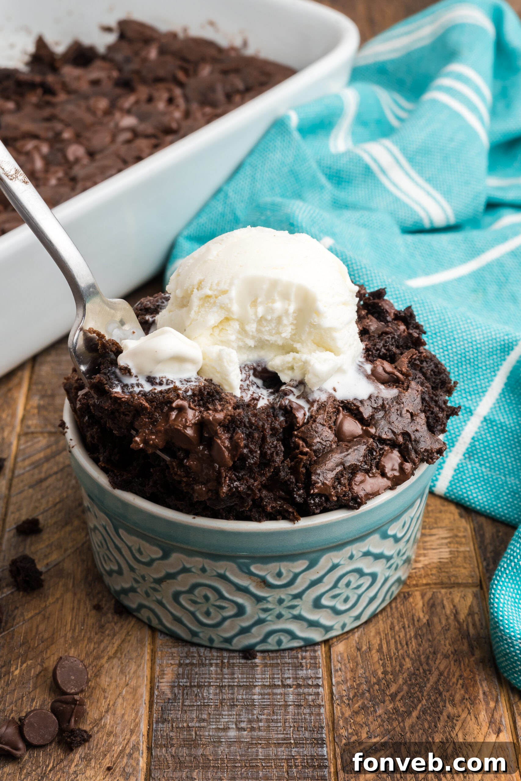 A silver fork poised to take a bite from a serving of rich chocolate dump cake, highlighting the cake's appealing texture.