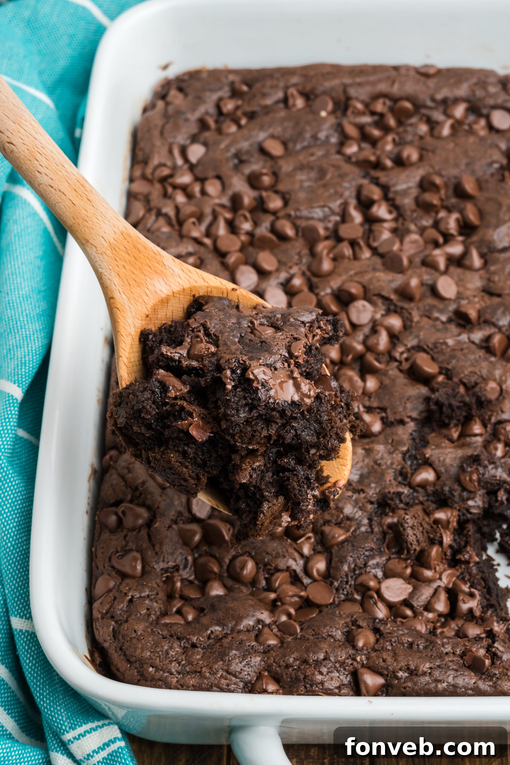 A close-up view of a wooden spoon lifting a scoop of the luscious chocolate dump cake, showing its gooey, irresistible consistency.