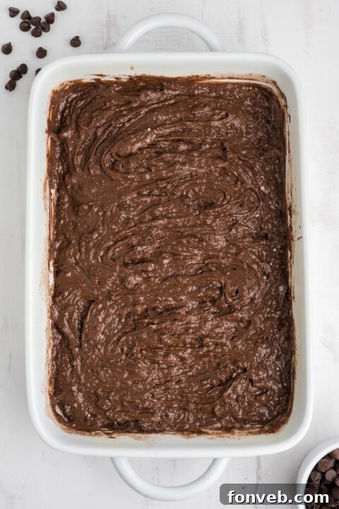 Step-by-step image showing the melted butter and milk being poured over the dry ingredients in the baking dish.