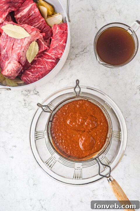 Step-by-step image of straining the Birria sauce to ensure a smooth consistency.