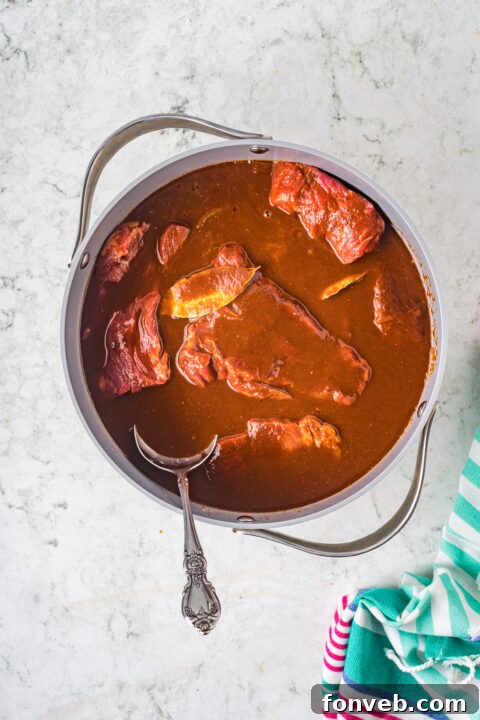 Step-by-step image of the Birria meat simmering in the rich sauce.