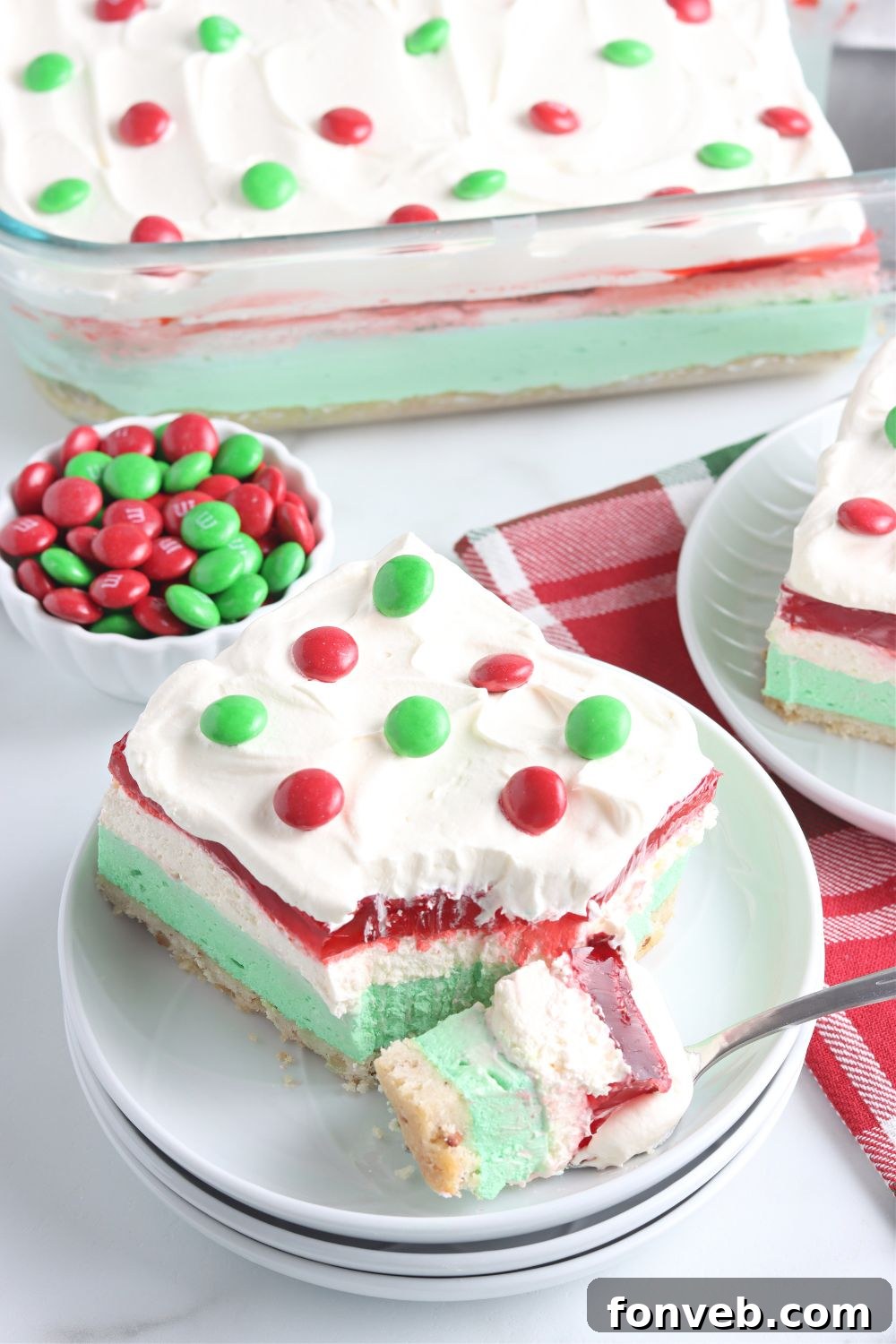 A close-up of a bite of Christmas dessert lasagna on a fork, showing the clear, distinct layers.