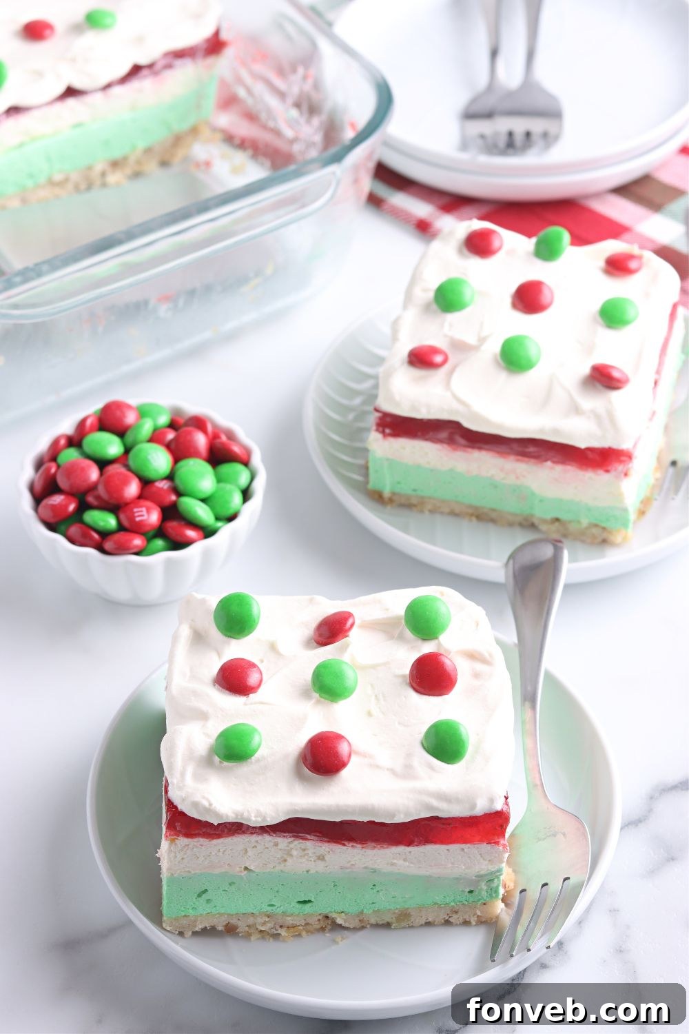 Plates on a table with slices of the vibrant jello dessert for Christmas.