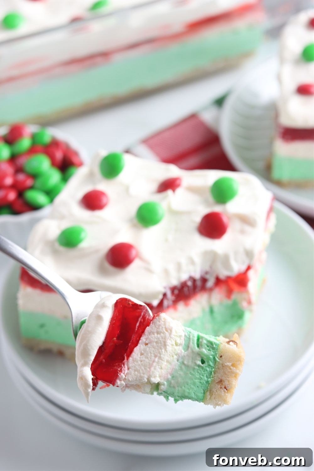 A fork holding a bite of Christmas dessert above a plate, ready to be eaten.