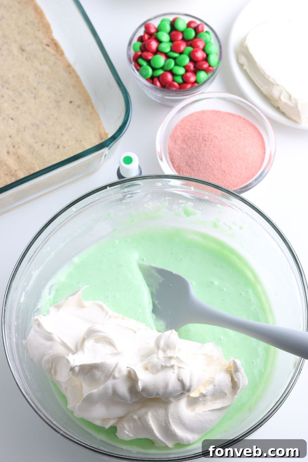 Folding whipped cream into a green Jello and cream cheese mixture.