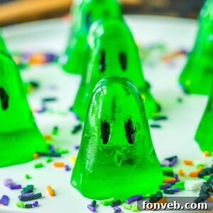 ghost shaped jello shots on table with Halloween sprinkles around it
