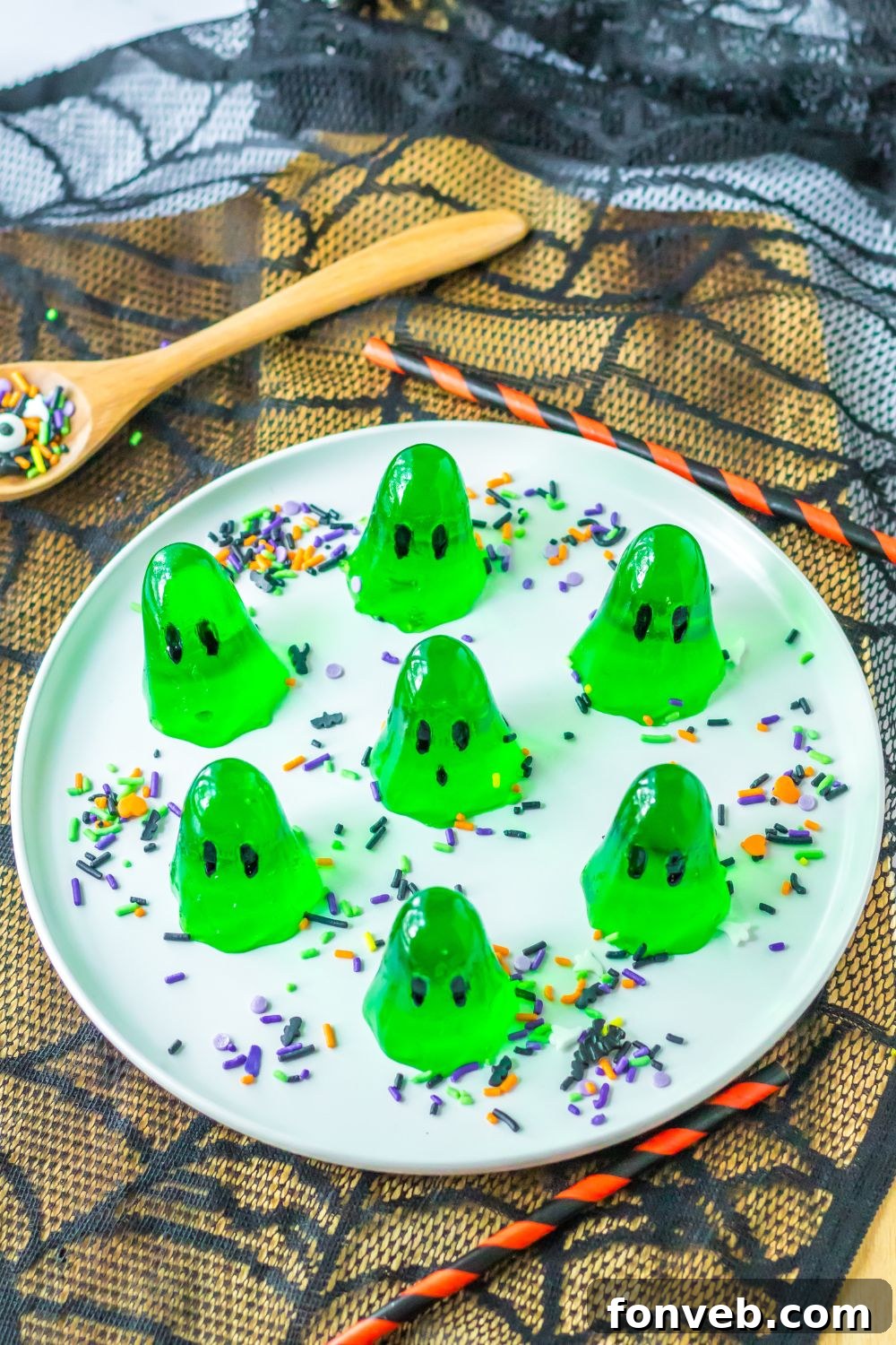 Spooky Spirit Shooters 9 A platter brimming with vibrant green ghost jello shots, elegantly placed on a spider web coaster for a spooky presentation.