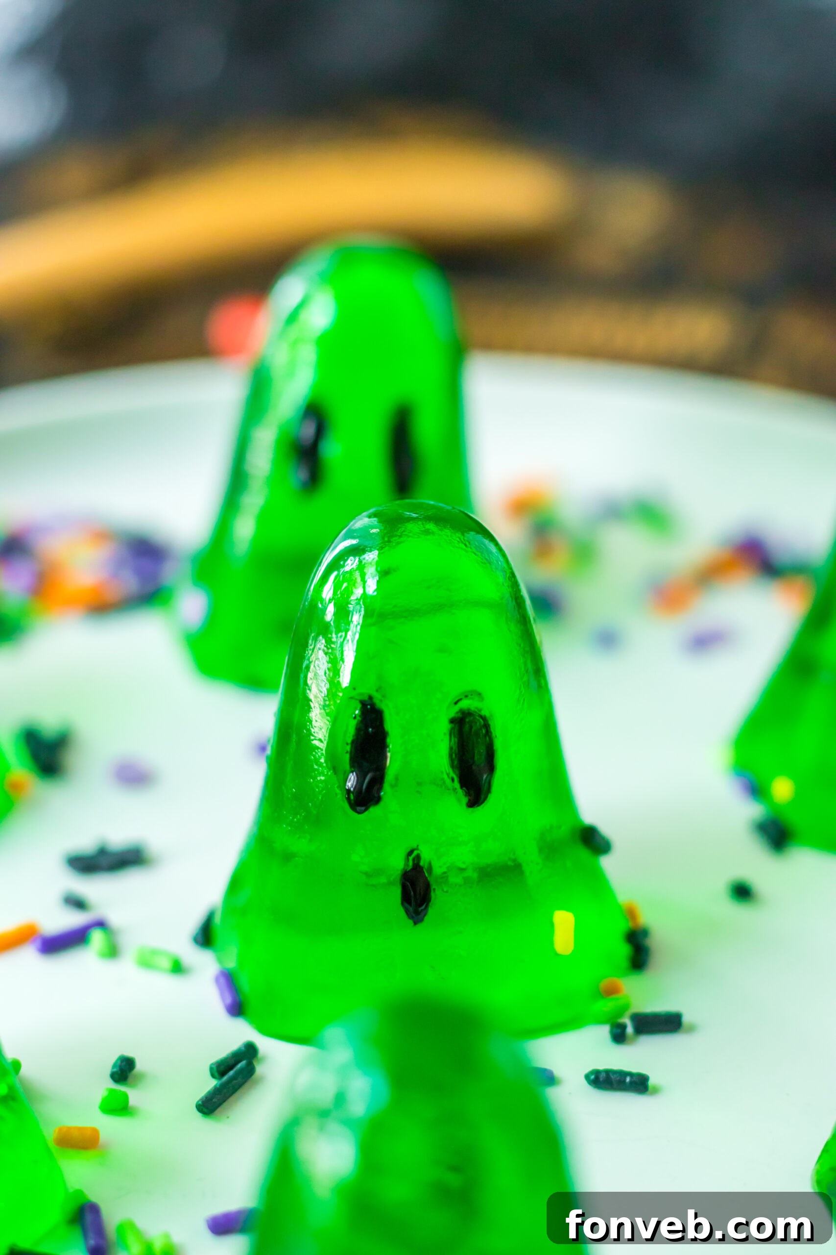 Spooky Spirit Shooters 10 A large platter generously filled with green ghost-shaped jello shots, artfully sprinkled with festive Halloween decor.