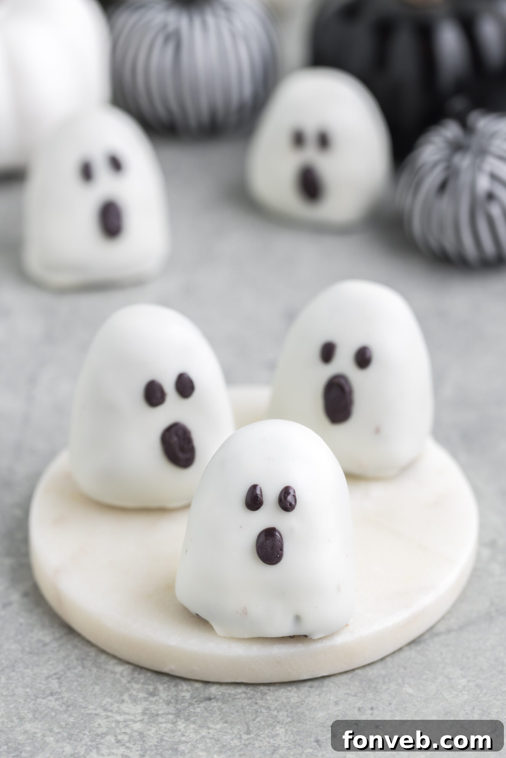 Spooky Oreo truffles on a table with fabric pumpkins in the background