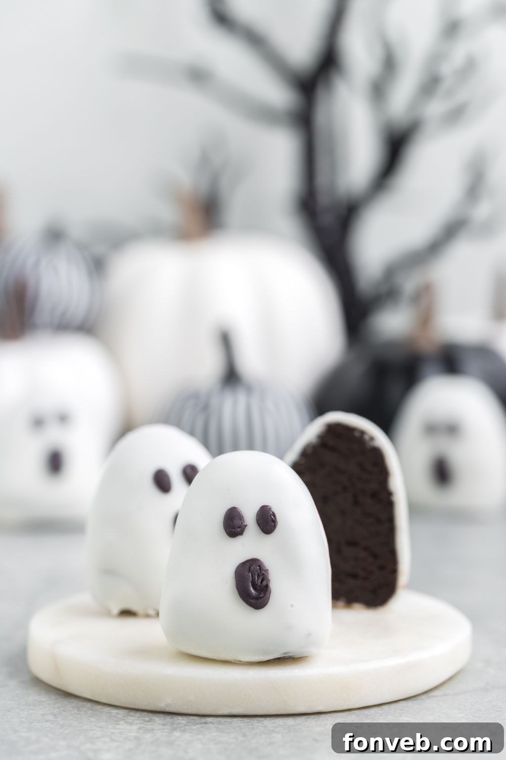 A sliced truffle on a marble cutting board with more truffles spread on a table in the background