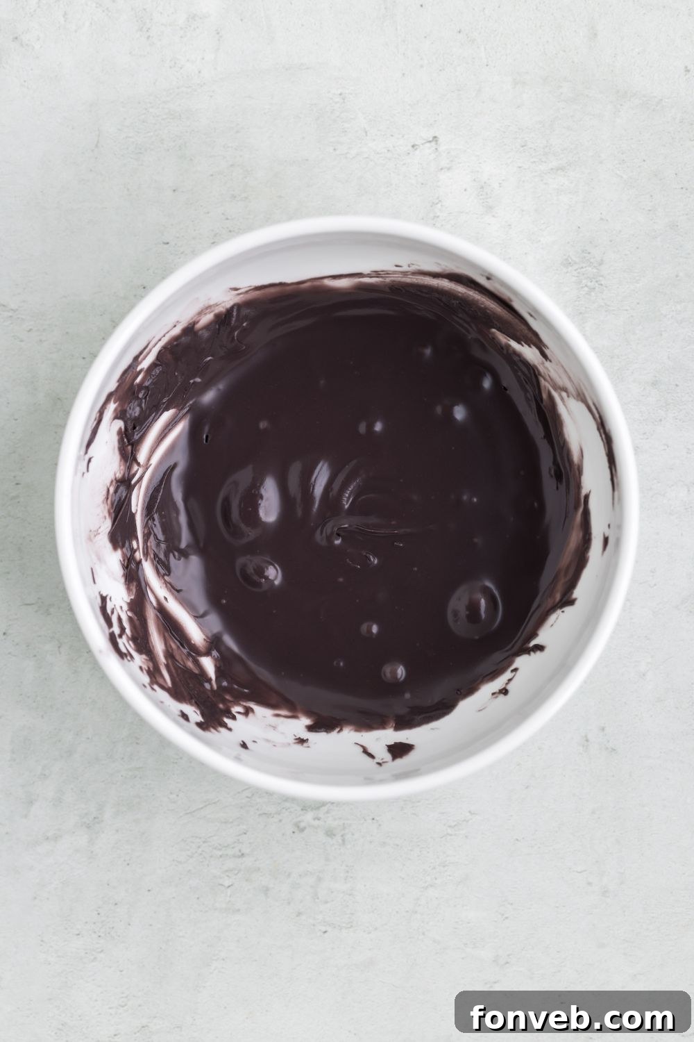 Melted black candy melts in a white bowl on a table