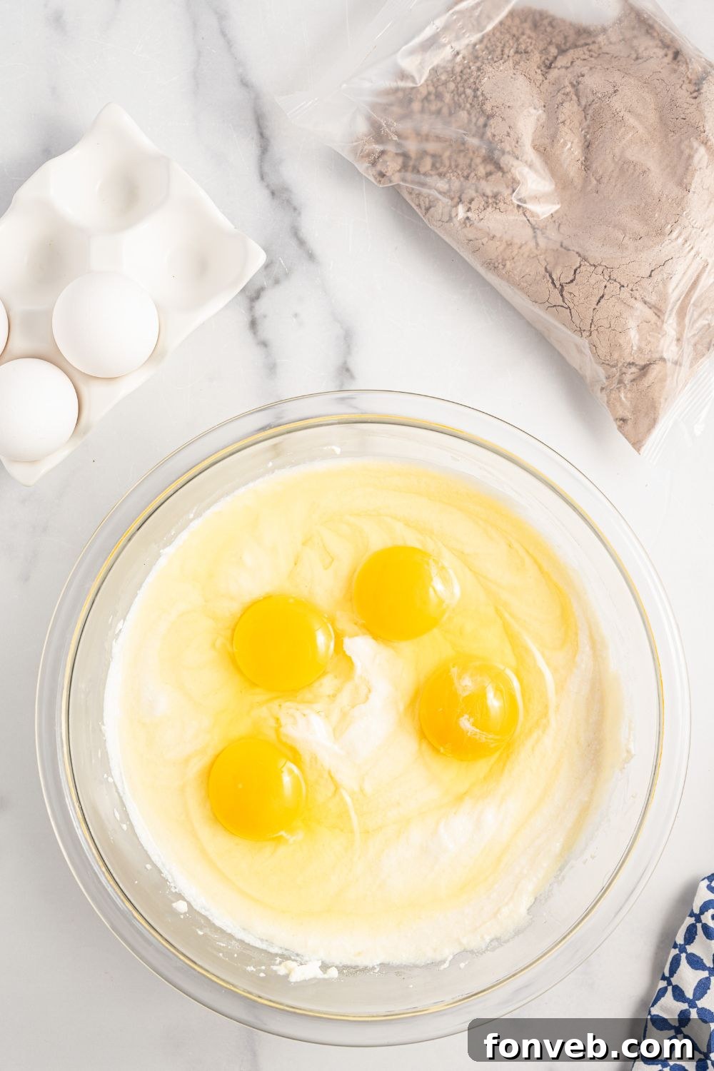 Eggs being mixed into the ricotta cheese mixture in a glass bowl, creating a smooth batter.