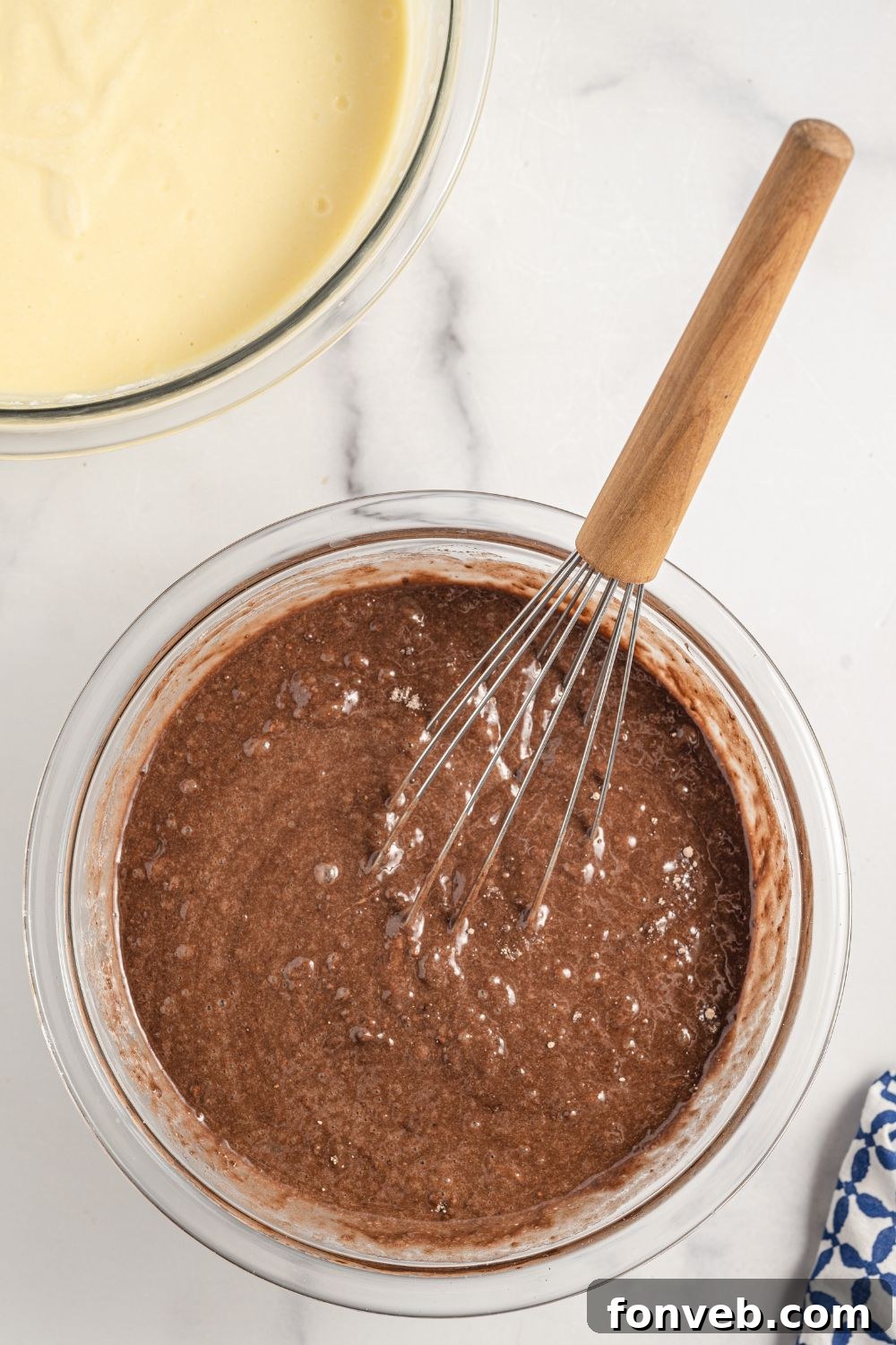 Chocolate cake mix being whisked in a glass bowl with other wet ingredients.