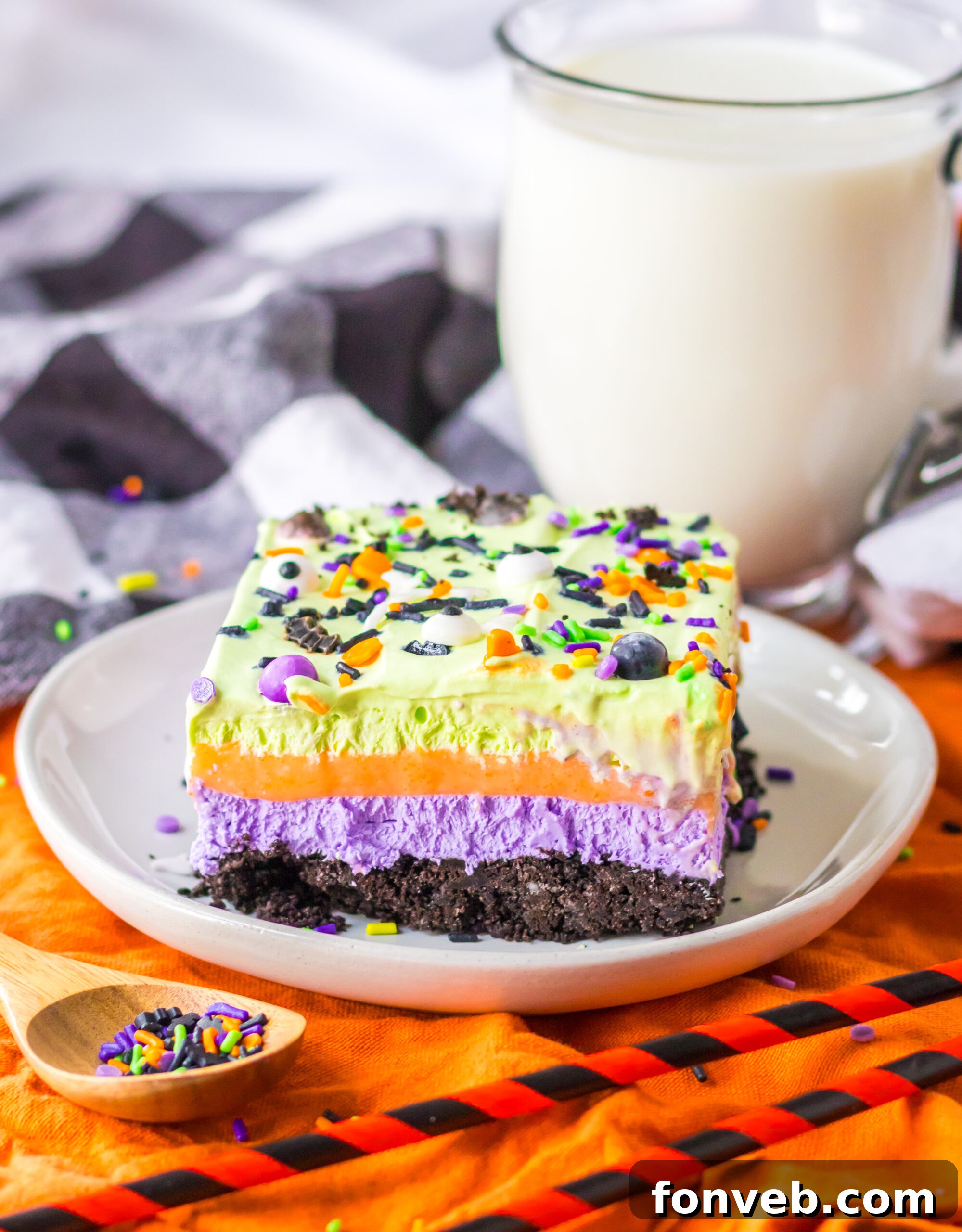 Halloween Lush Dessert sliced and placed on plate with sprinkles in a bowl on side and a glass of milk