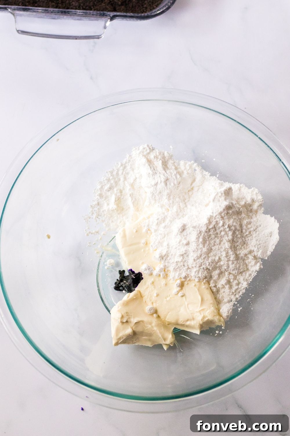 cream cheese mixture in bowl with a dab of food coloring in a glass bowl 