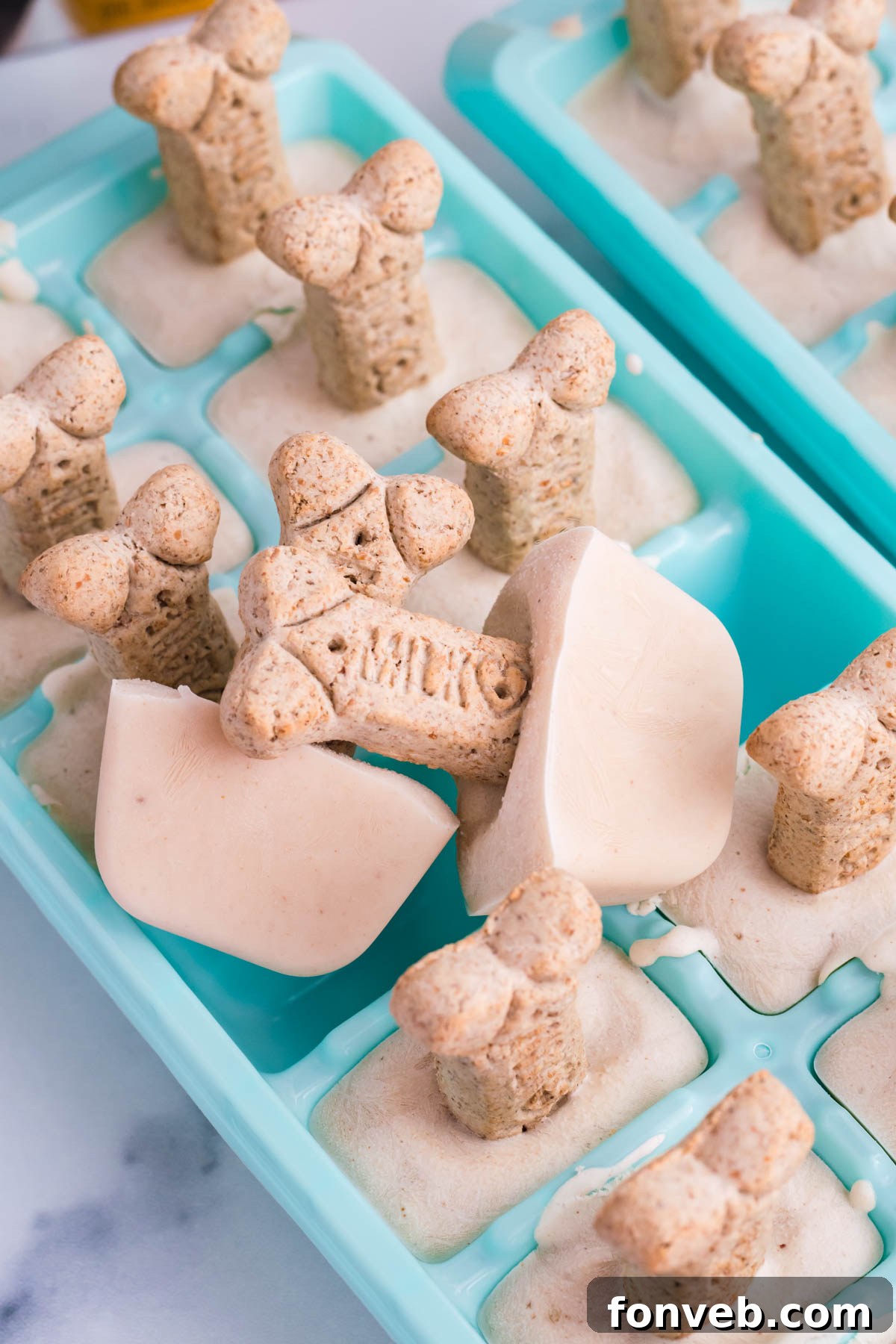 Dog ice cream on a milkbone stick sitting on a blue ice cube tray