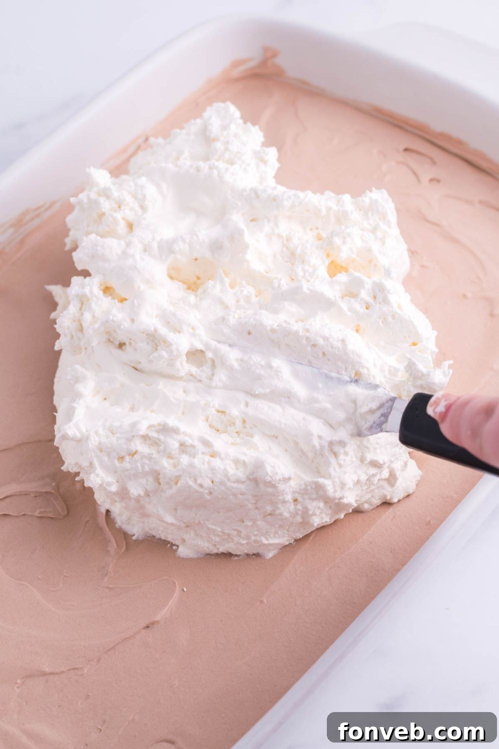 spreading whipped cream on top of french silk topping on brownies 