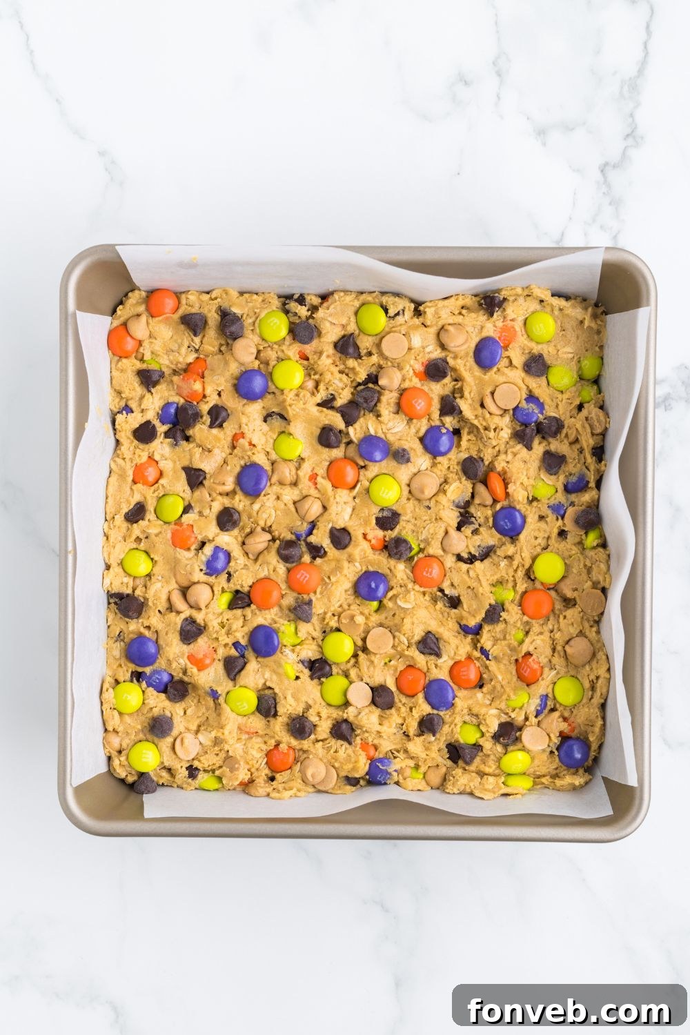 Overhead shot of Halloween Monster Cookie Bars spread evenly in a baking pan before baking.