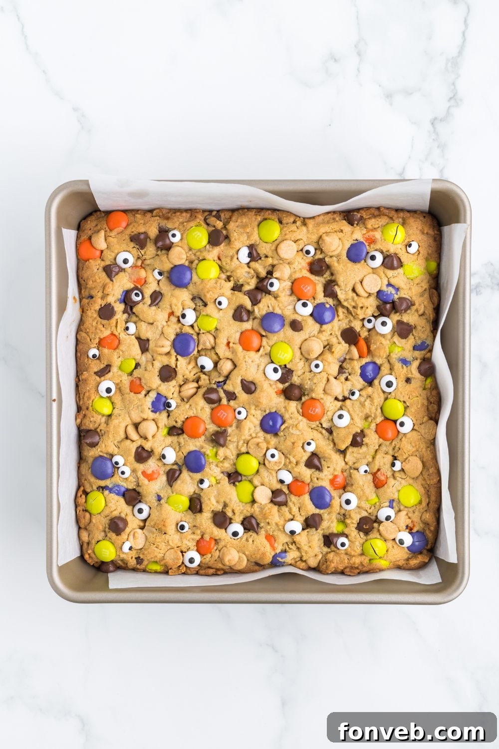Decorated Halloween Monster Cookie Bars in an 8x8 pan, freshly baked with candy eyes.