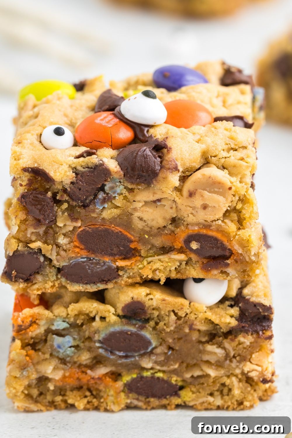 Chewy cookie bars stacked on top of each other on a table, with additional cookie bars scattered around.