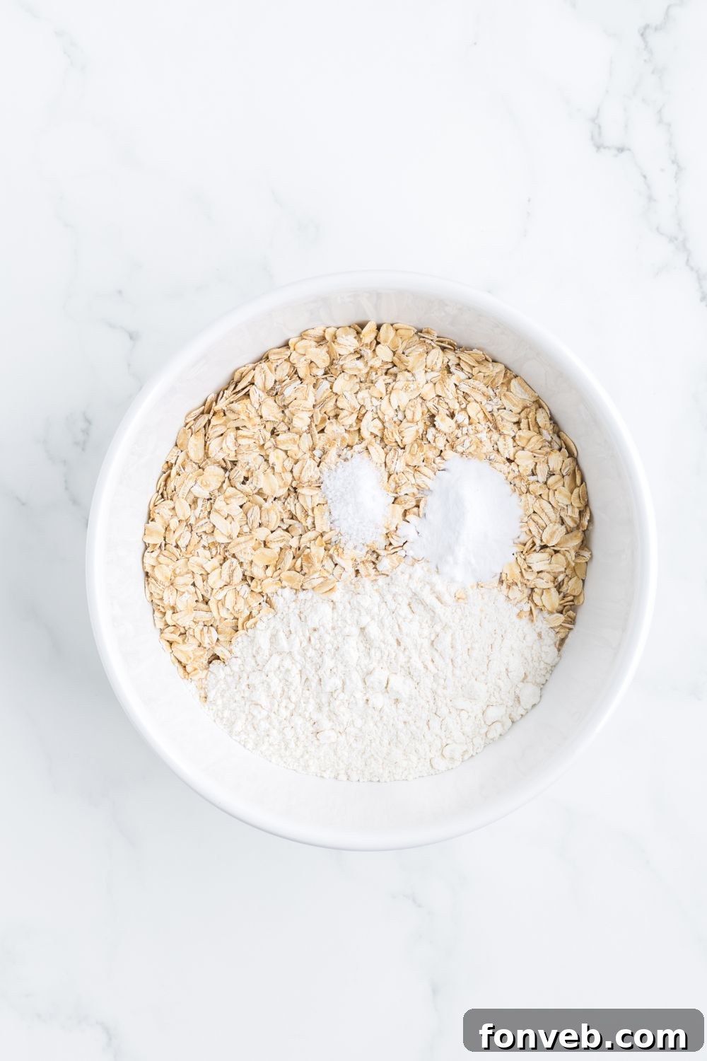 Dry ingredients for cookies in a white bowl, ready to be mixed.