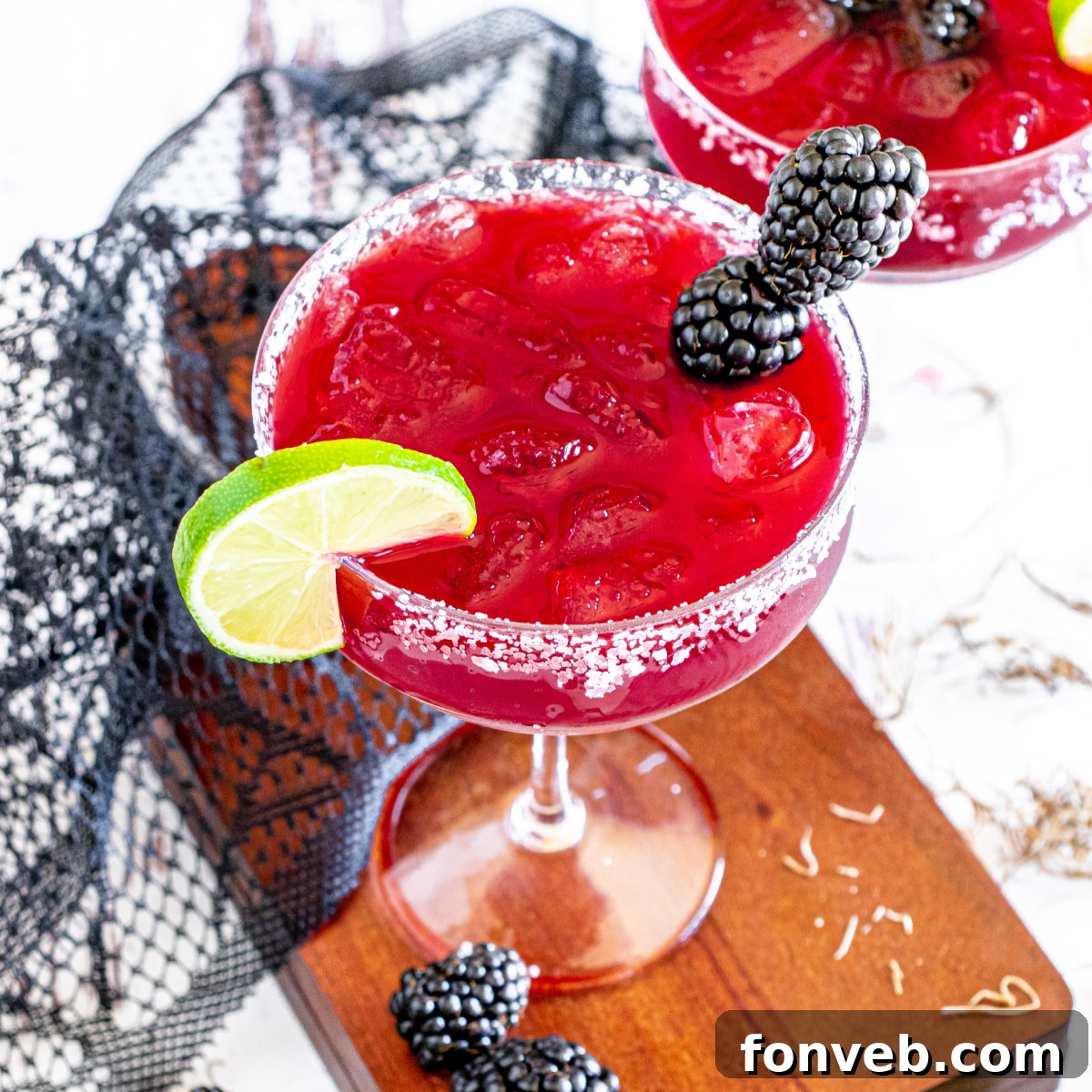 Magic Potion Margarita 2 Vibrant Sanderson Sisters Margarita in a glass, ready for a Halloween celebration, adorned with blackberries and lime.