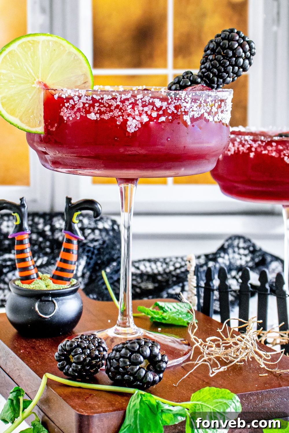 Magic Potion Margarita 15 Side view of two Sanderson Sisters Margaritas in glasses on a table, with a festive atmosphere.