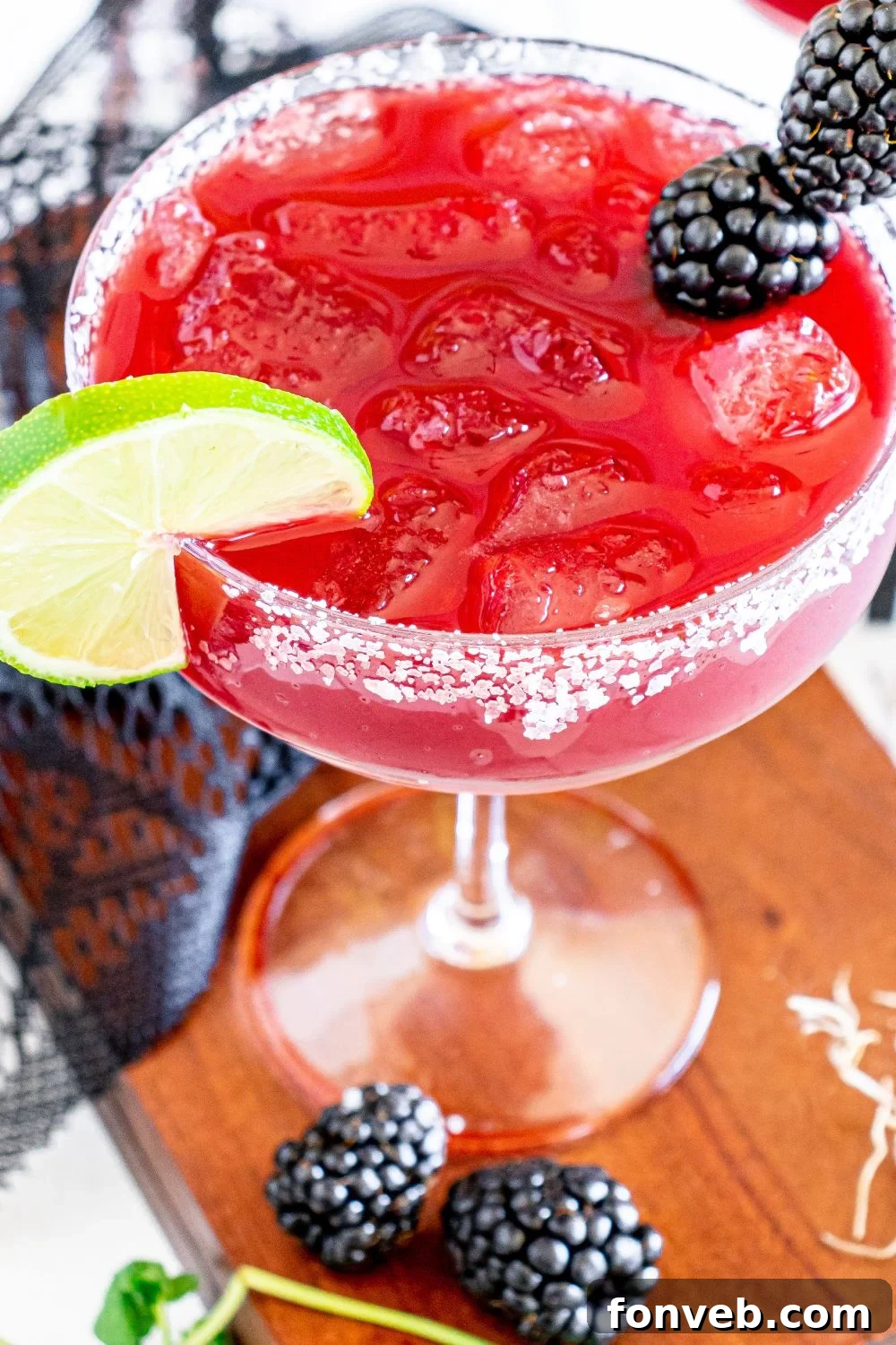 Magic Potion Margarita 16 A high-angle, close-up view of a Sanderson Sisters Margarita, highlighting its vibrant color, ice, and blackberry garnish.