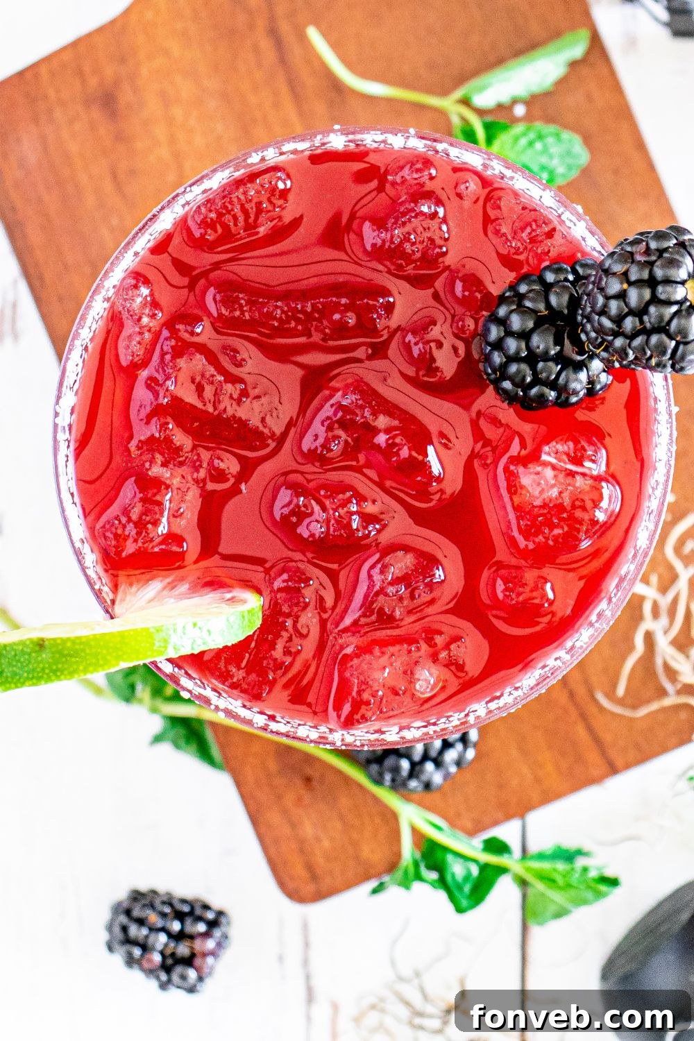 Magic Potion Margarita 17 Overhead shot of a Hocus Pocus drink with lime slices, fresh blackberries, and a sprig of rosemary on the side, creating a festive composition.