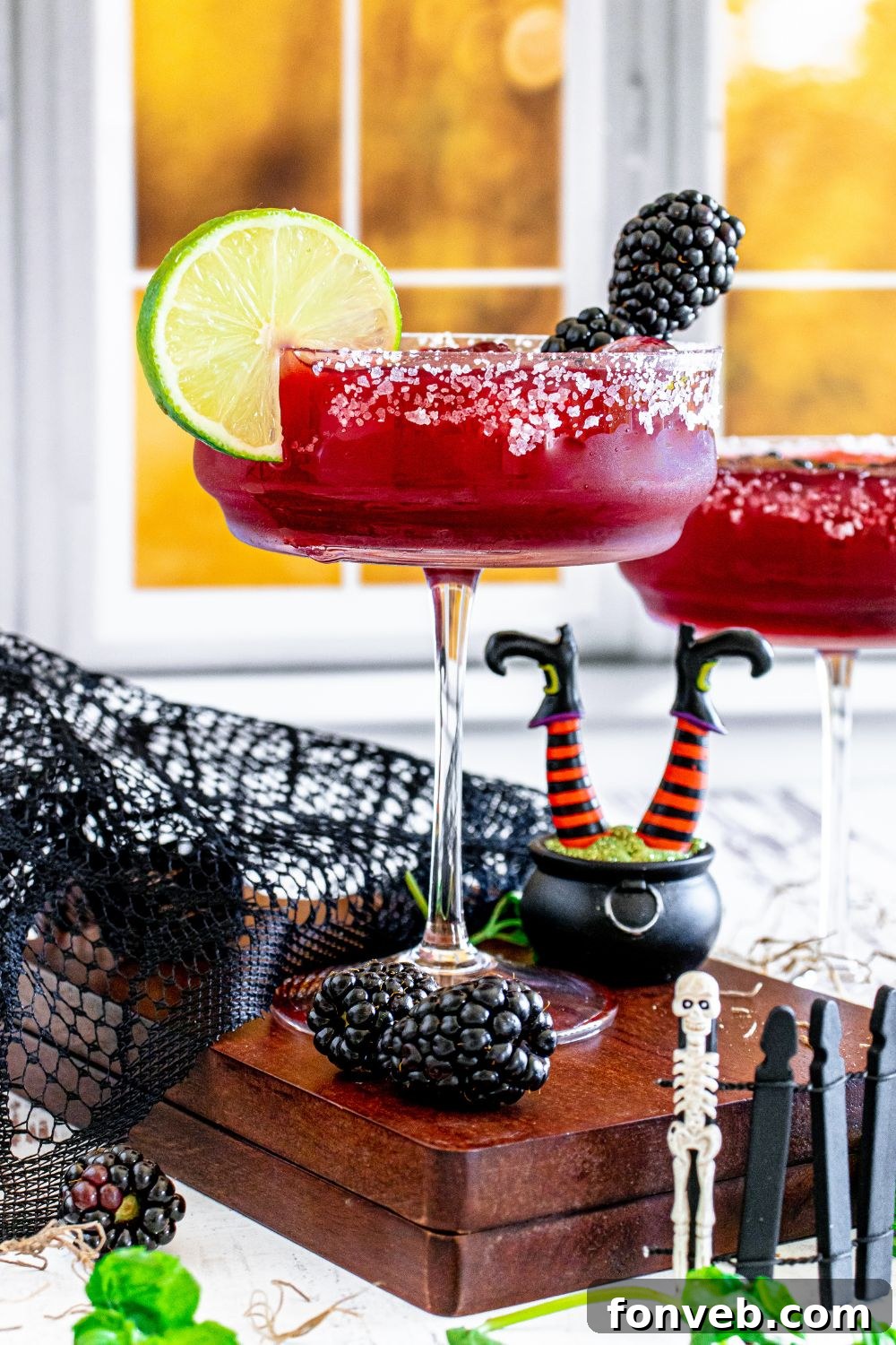 Magic Potion Margarita 4 Close-up of two Hocus Pocus blackberry margaritas in salt-rimmed glasses, garnished with lime and blackberries, surrounded by subtle Halloween decor.